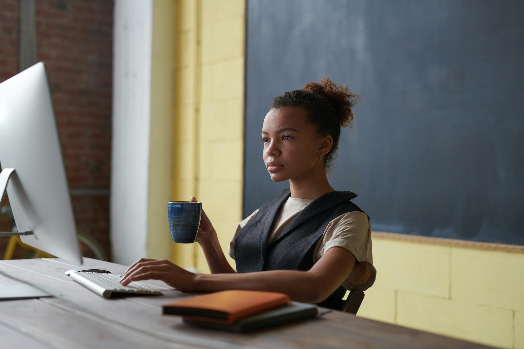 Woman holding a mug while typing on a keyboard