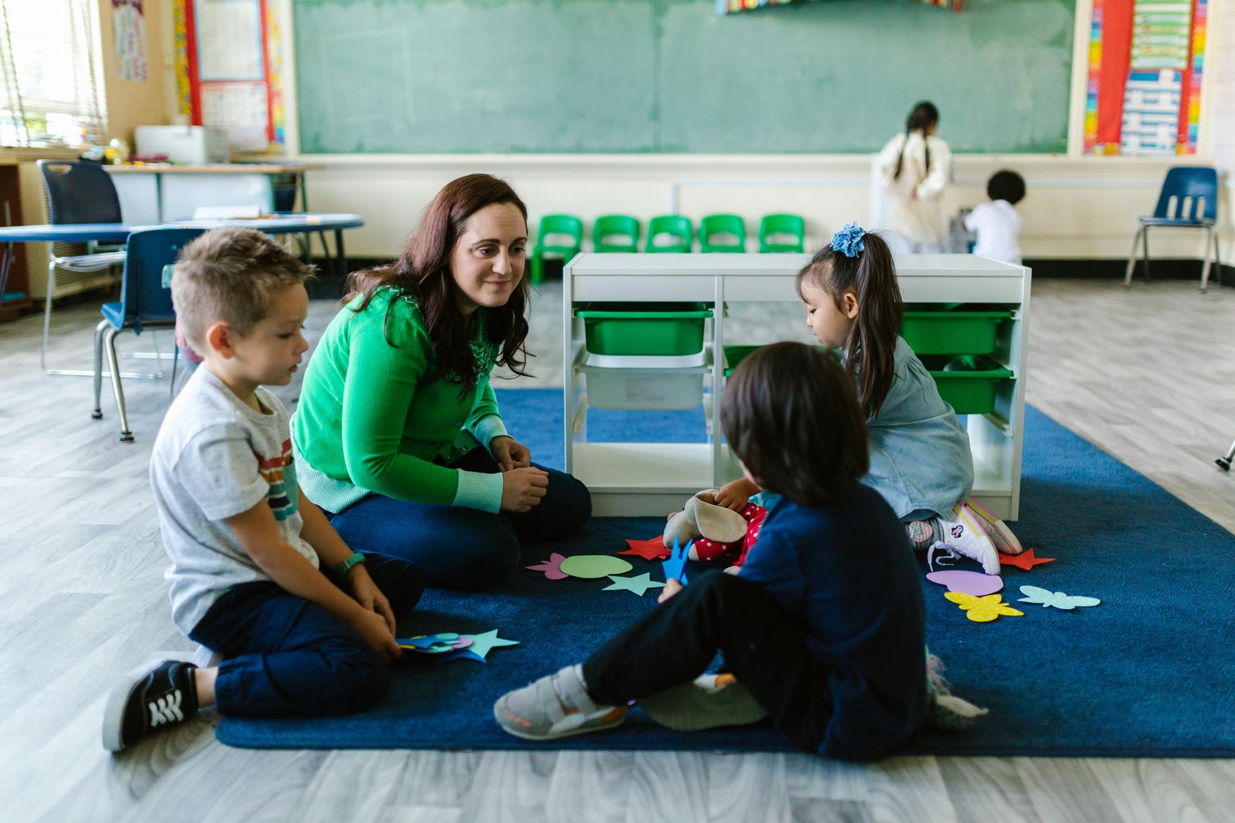 Teacher and students sitting on the floor while doing an art project