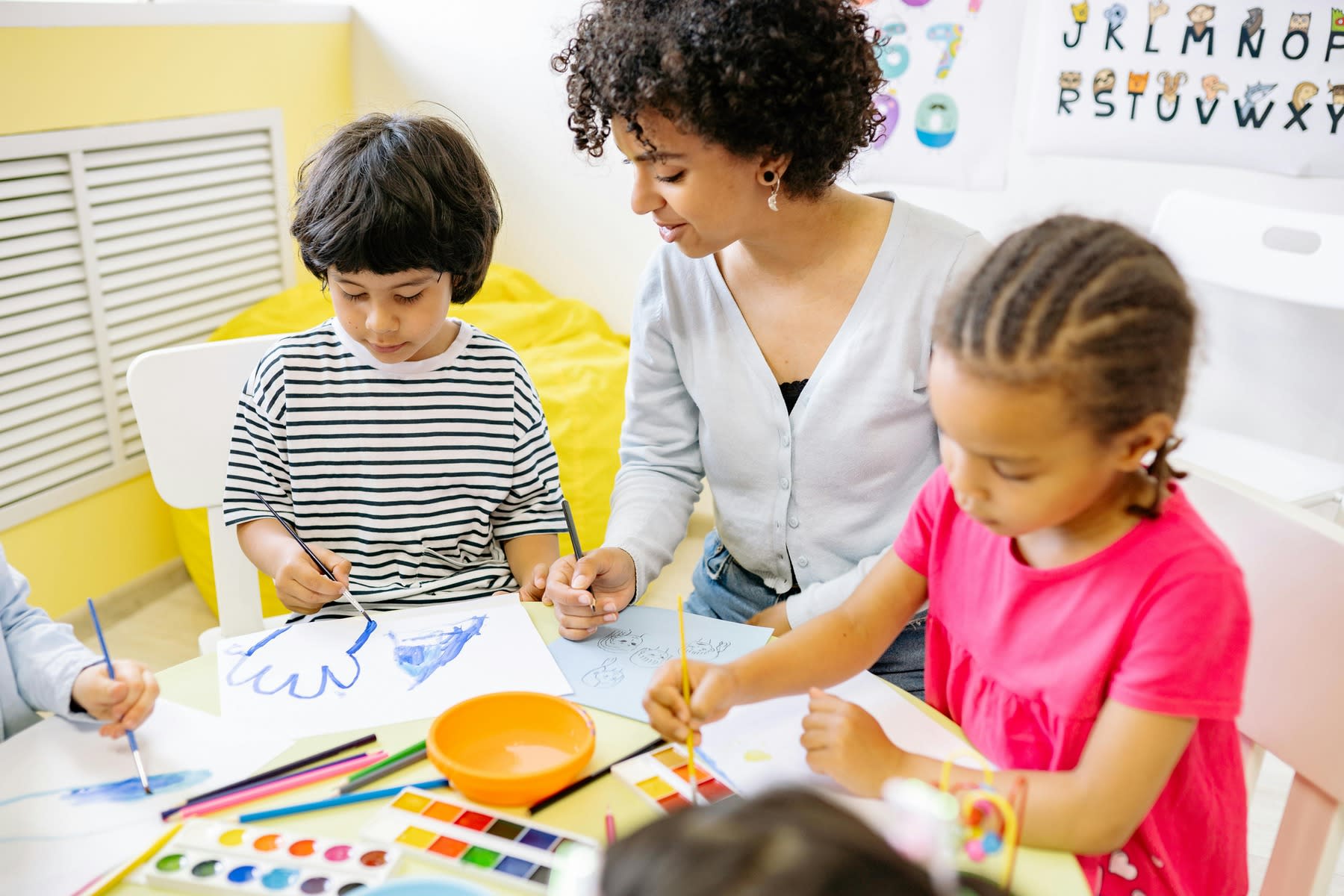 Students drawing during class, while their teacher is seated beside them