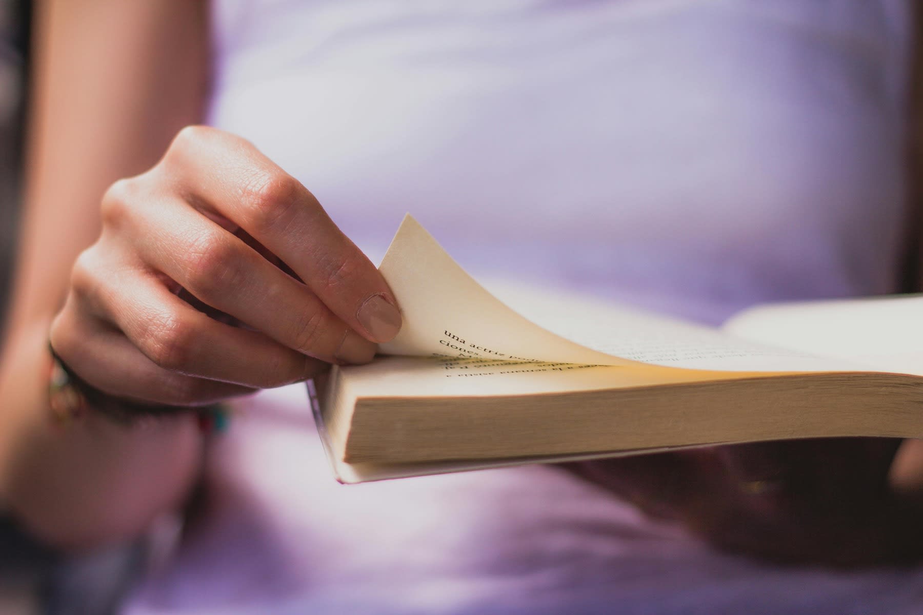 Woman about to turn the page of a book she's reading