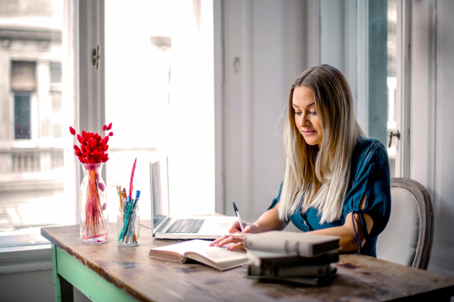 Woman writing down notes while reading a book