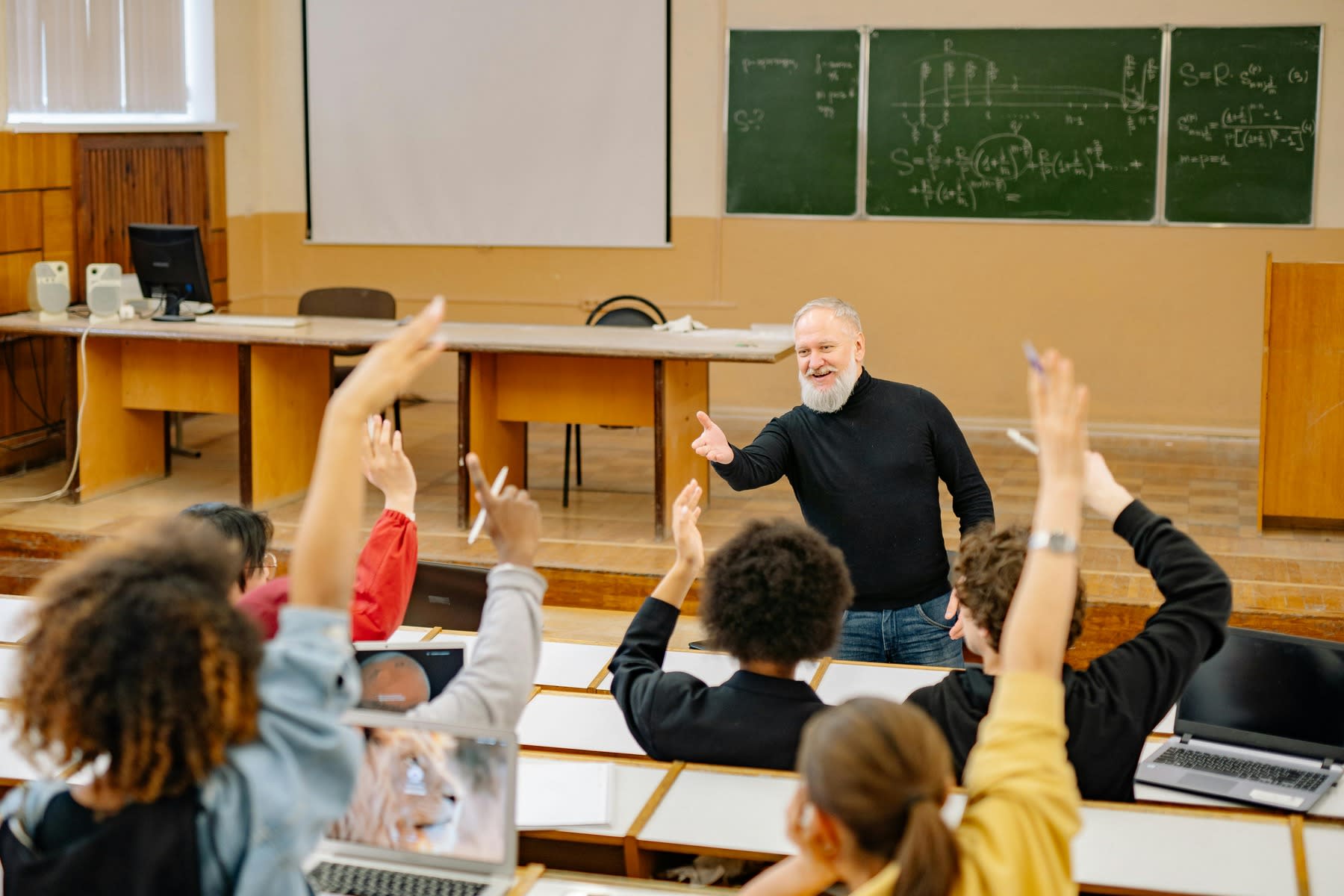 Students raising their hands, all hoping that their professor will pick them during class