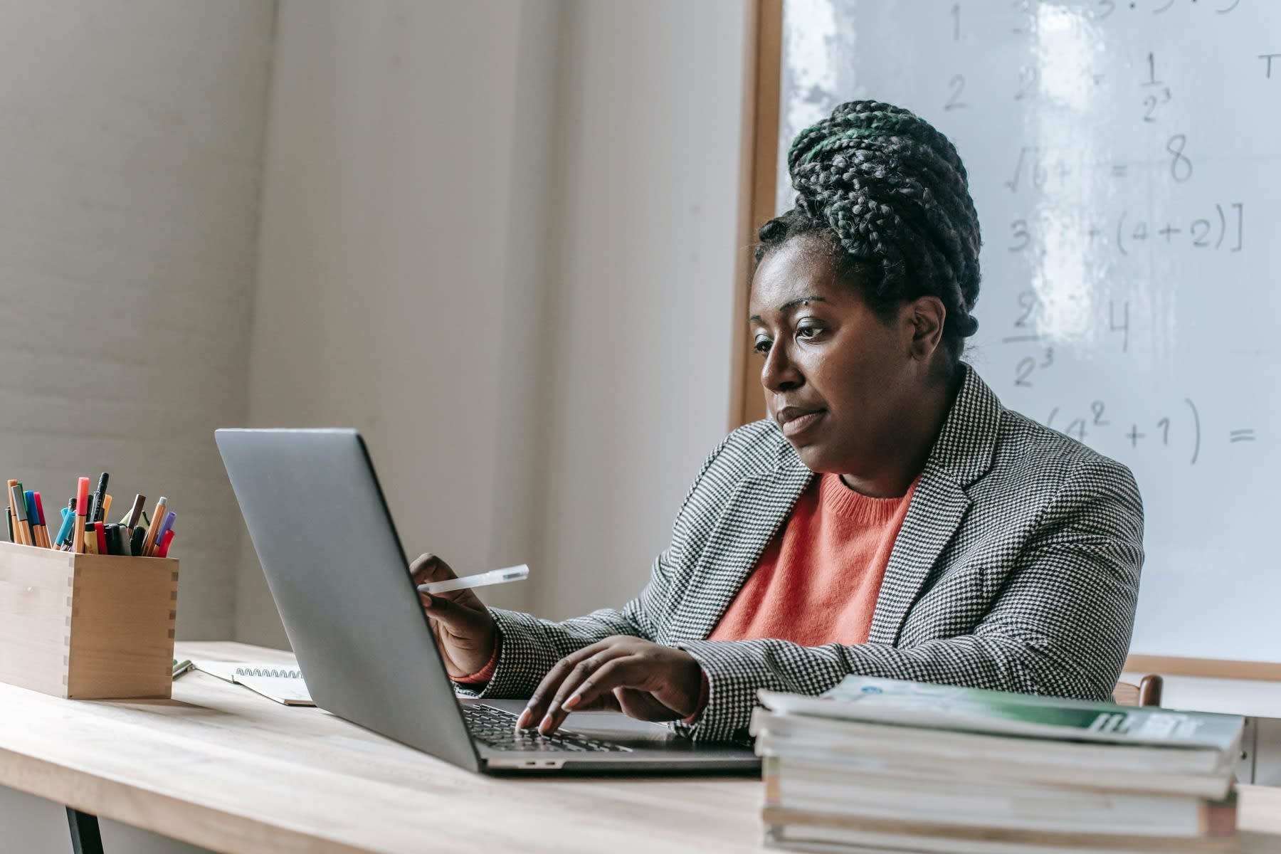 Female teacher using her laptop while seated in front of her classroom