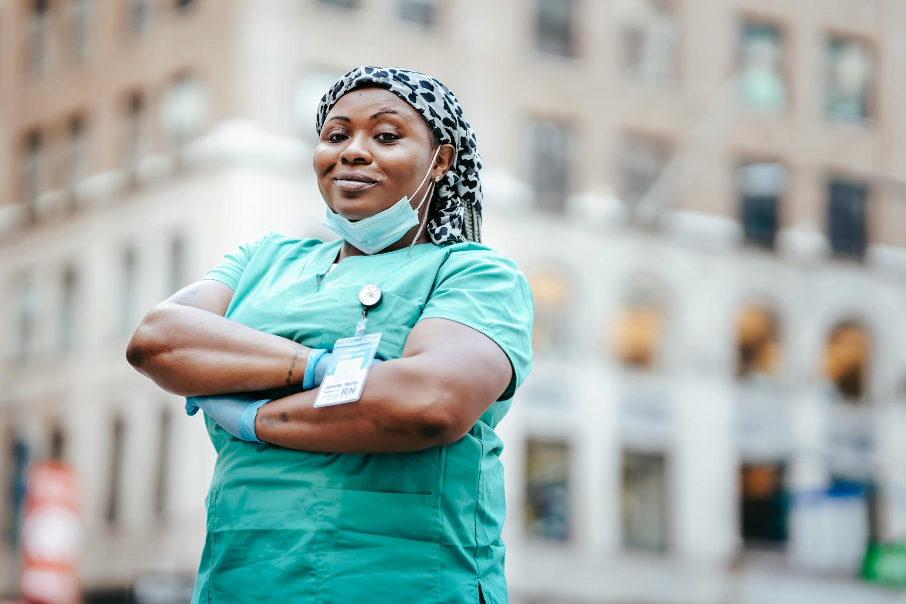 Woman wearing nursing scrubs, posing for a photo outside the hospital