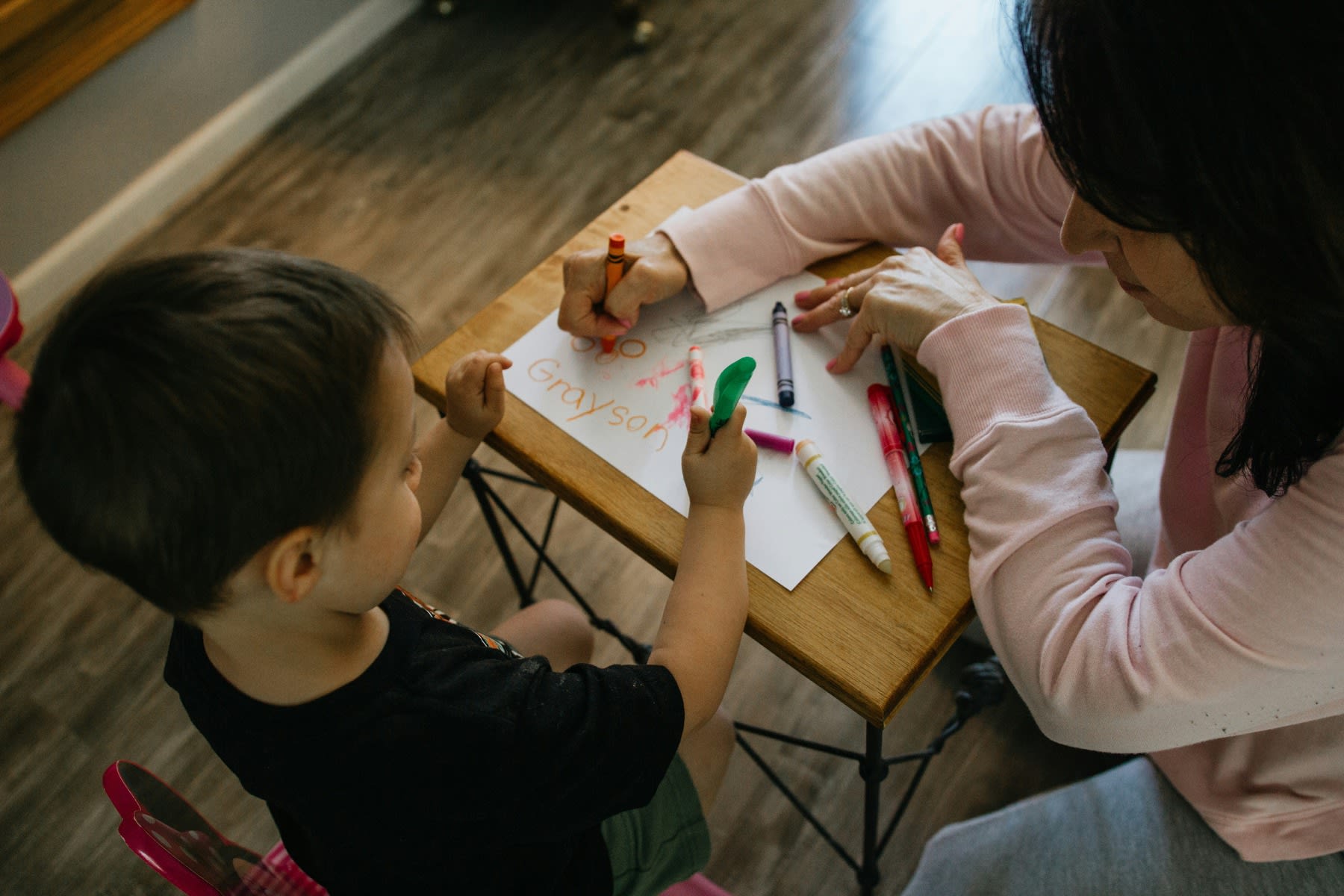 Woman coloring a sheet of paper with her young student