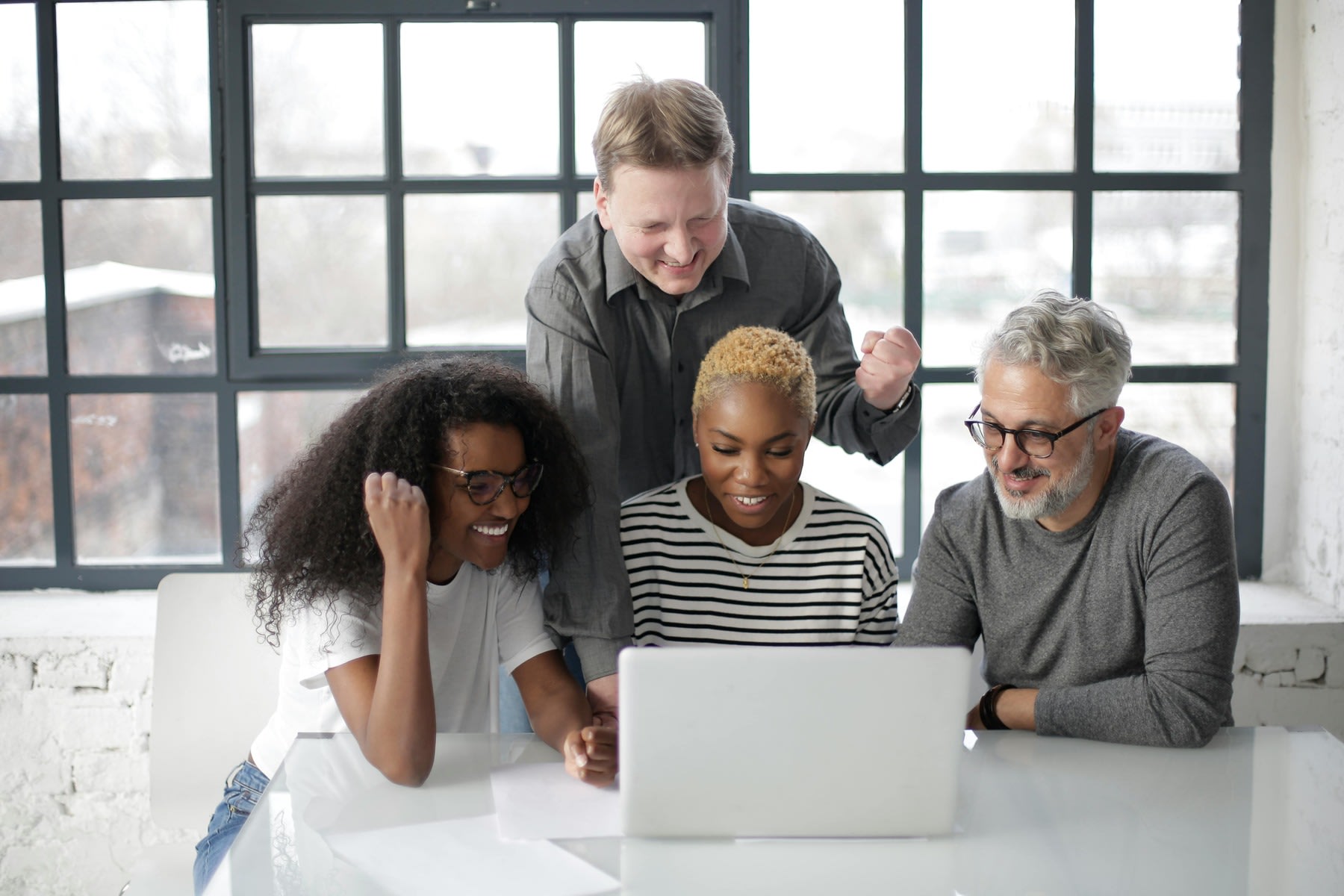 Group of people looking and smiling at a laptop's screen together