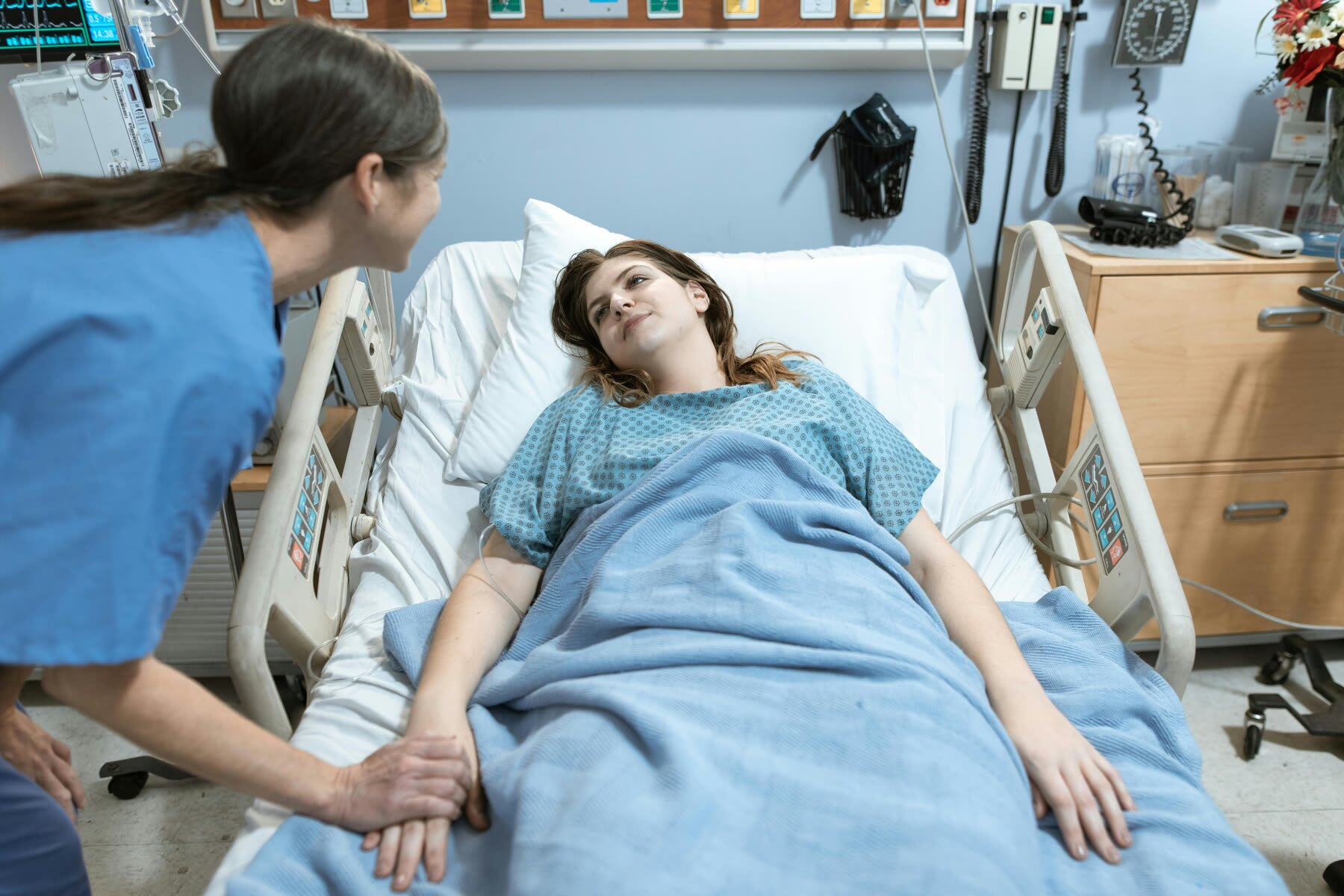 Nurse checking on a female patient lying on a hospital bed