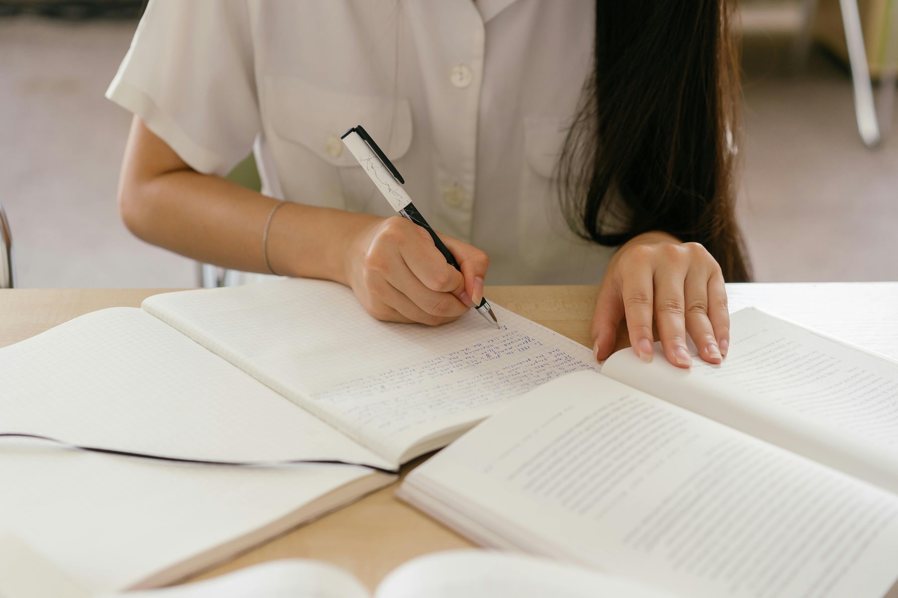Young woman taking notes while reading a textbook