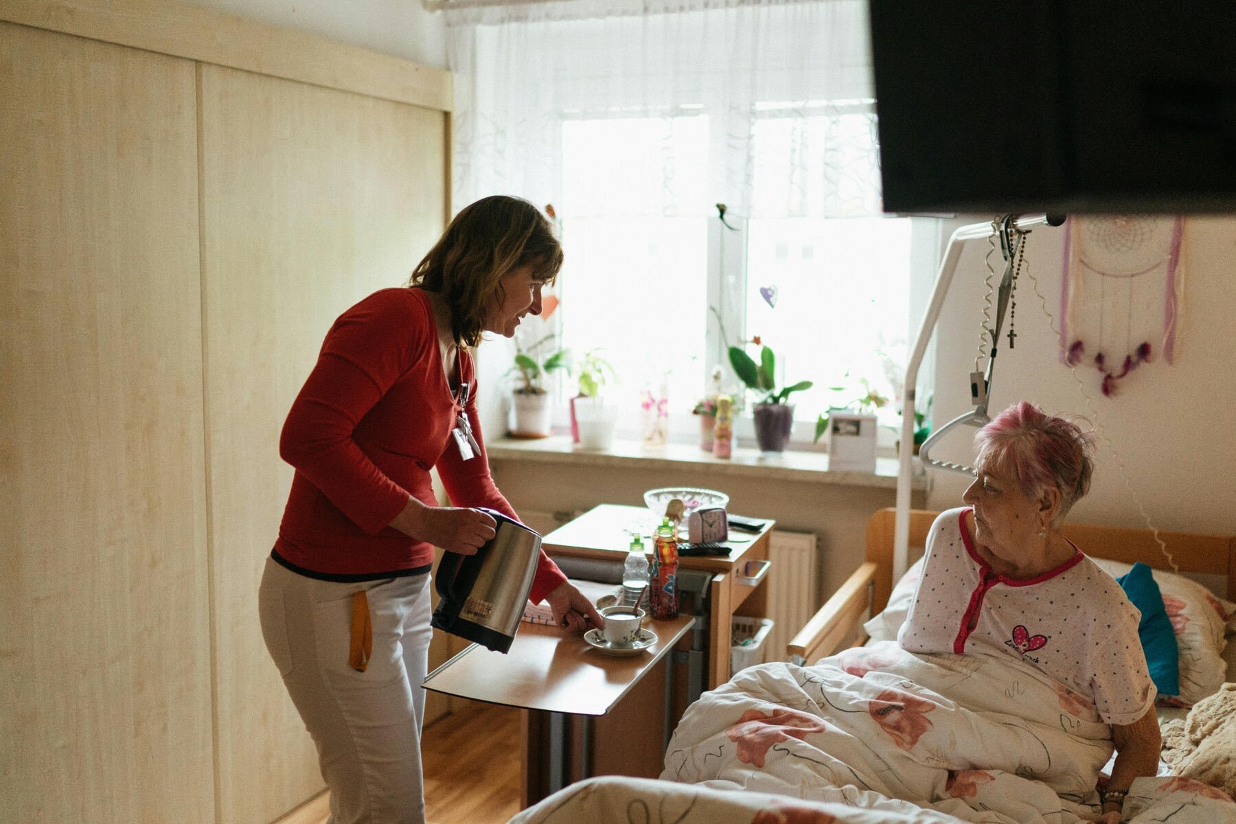 Nurse giving her elderly patient a cup of hot tea