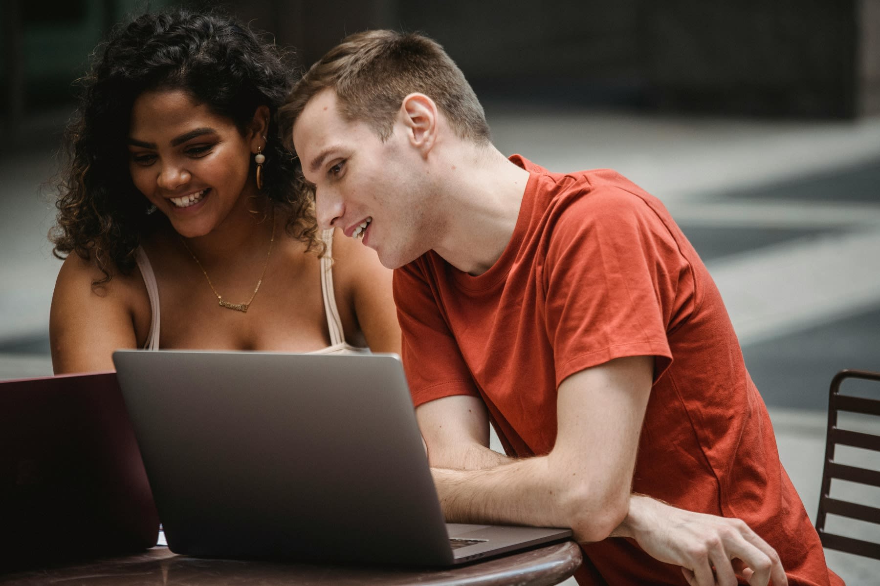 Two students studying outdoors with their laptop