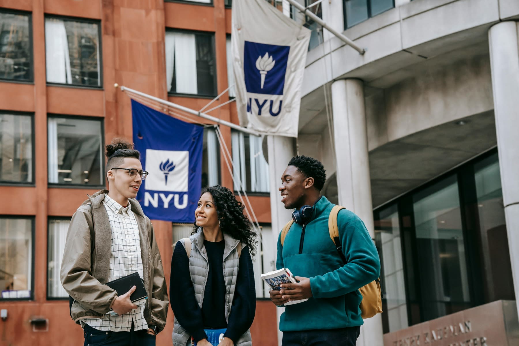 Three students standing outside the NYU building