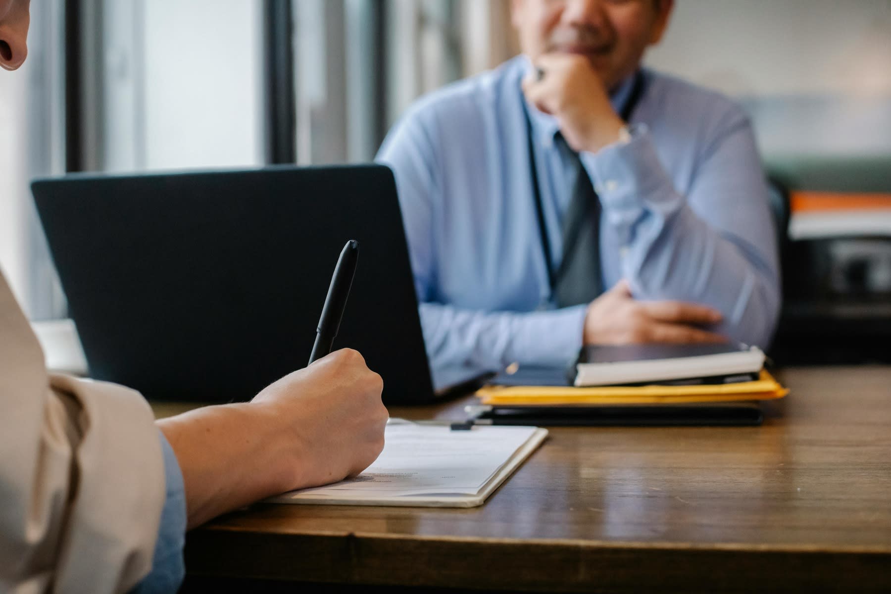 Woman signing a document while a male is sitting across her