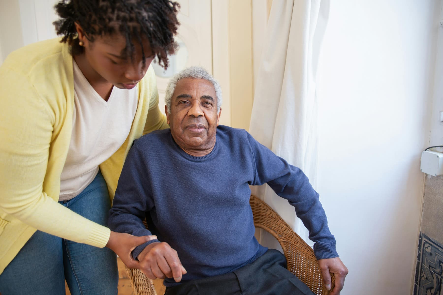 Female nurse assisting an elderly man out of a chair