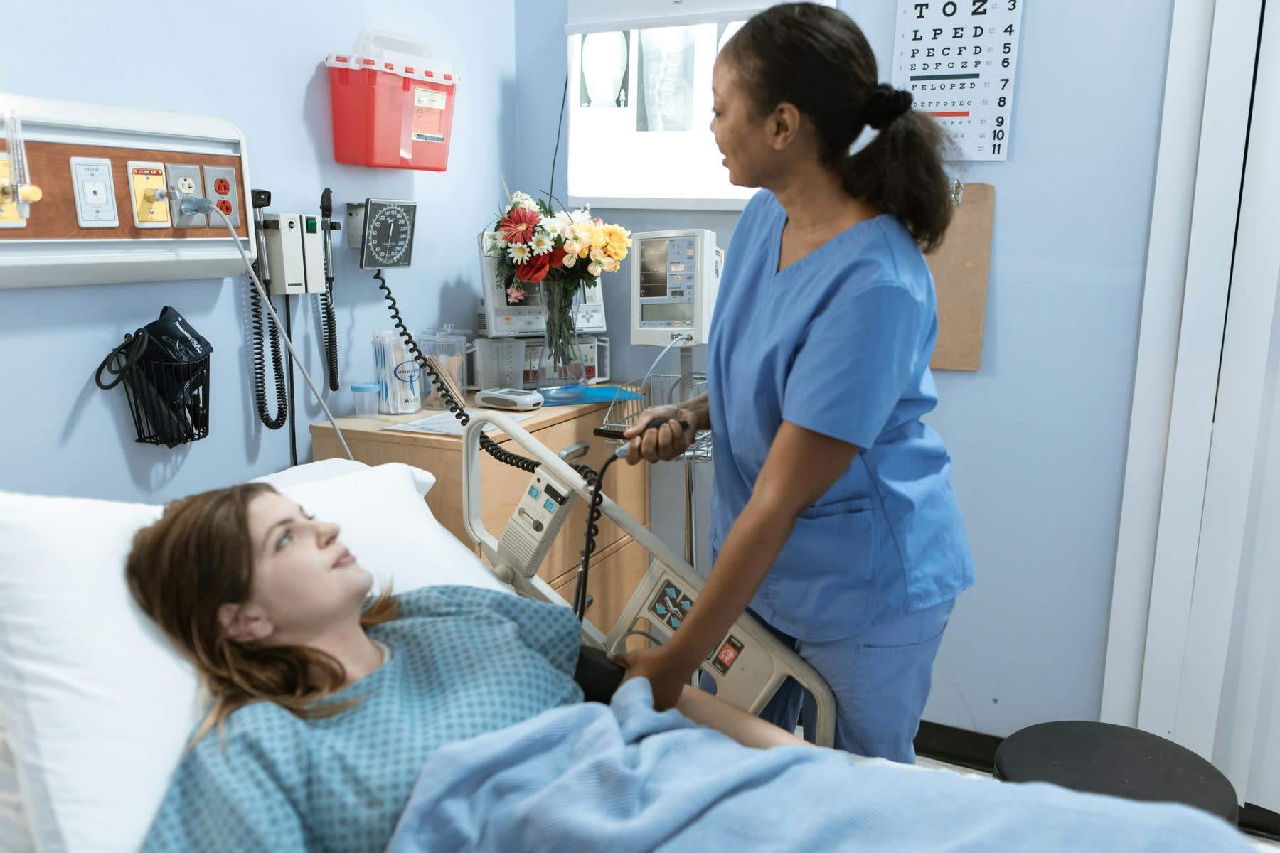 Female nurse checking a patient's blood pressure while she's lying down a hospital bed