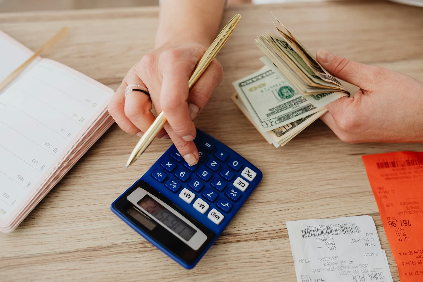 Person holding dollar bills while using a calculator