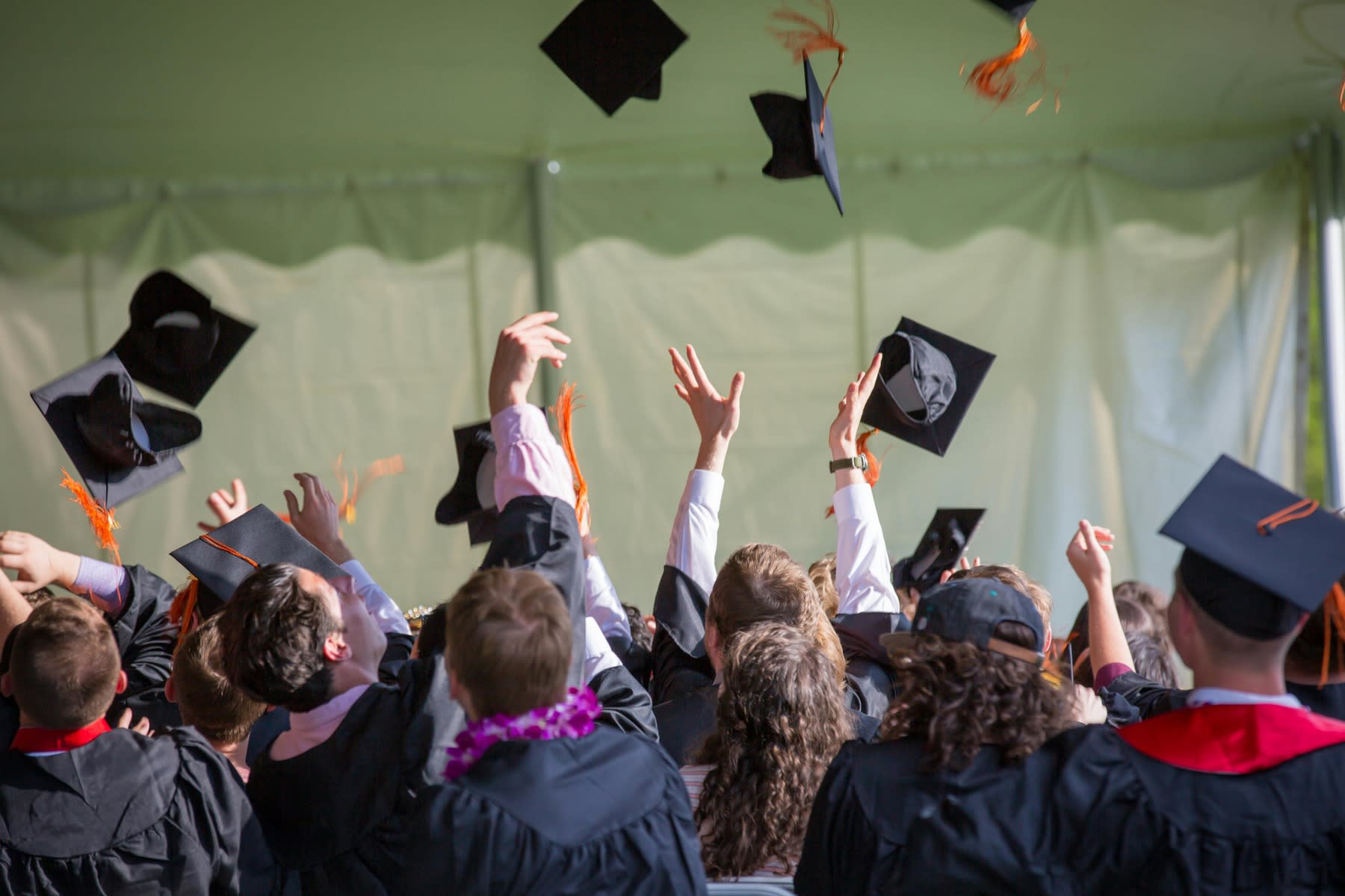 A group of graduate students throwing their graduation hats