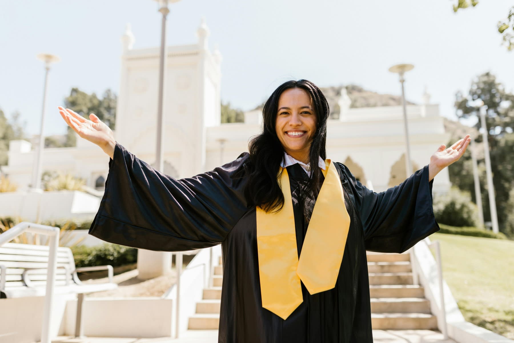 A woman wearing her graduation gown smiling