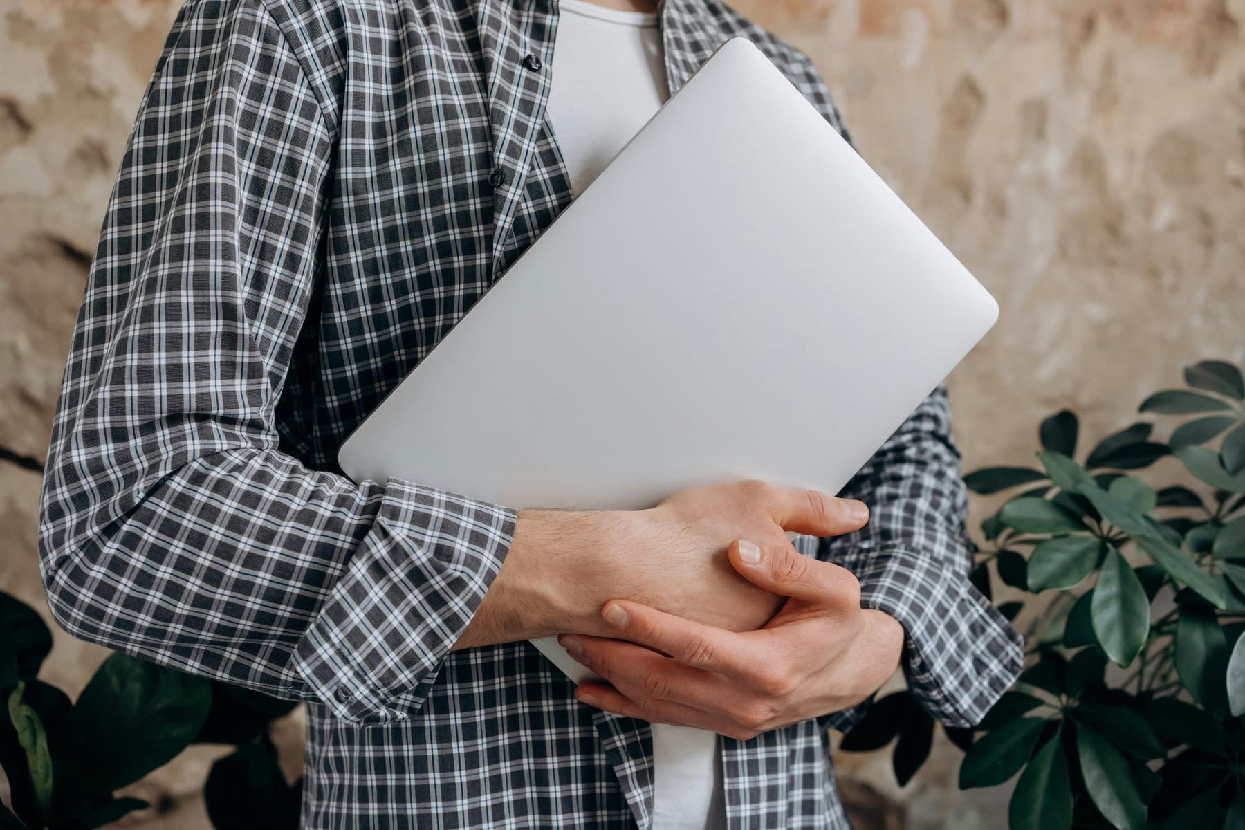 A man wearing plai holding a laptop