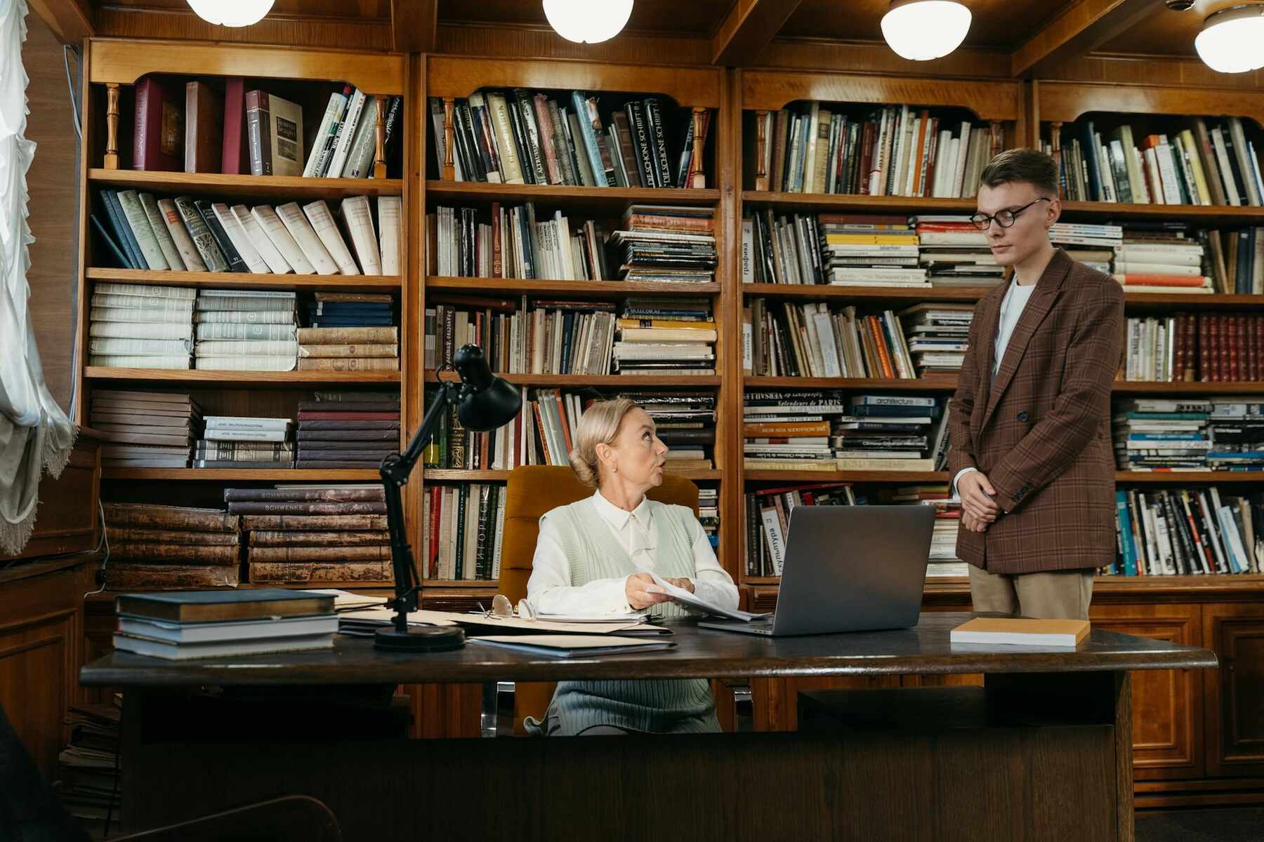 A man and woman together in front of a large bookcase filled with books