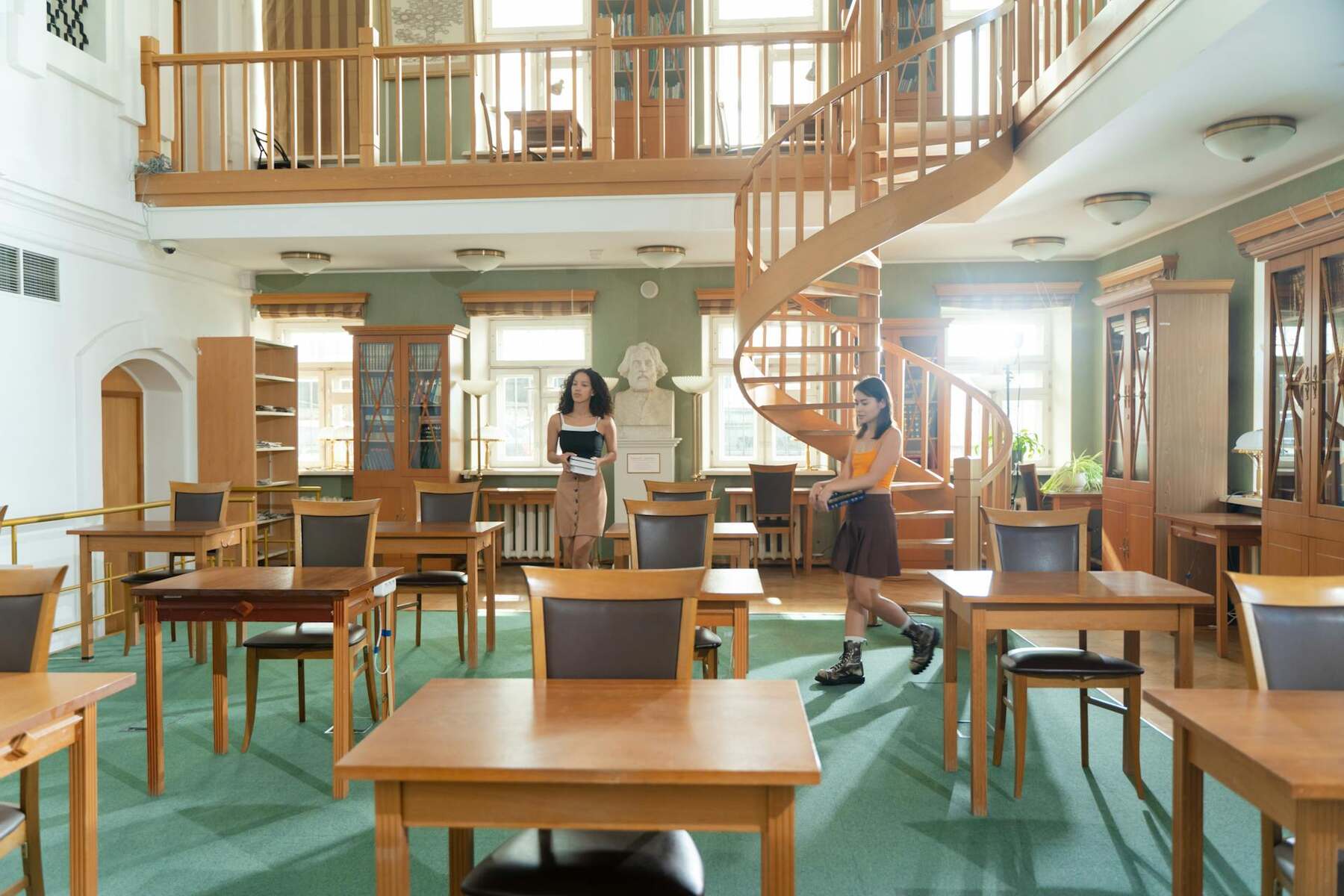 Two women students walking through their chair in a classroom