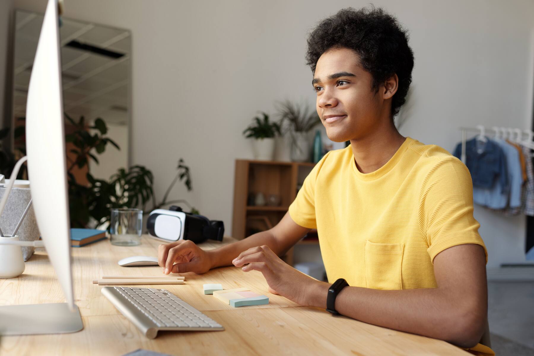 Man in a yellow t-shirt looking at his desktop monitor