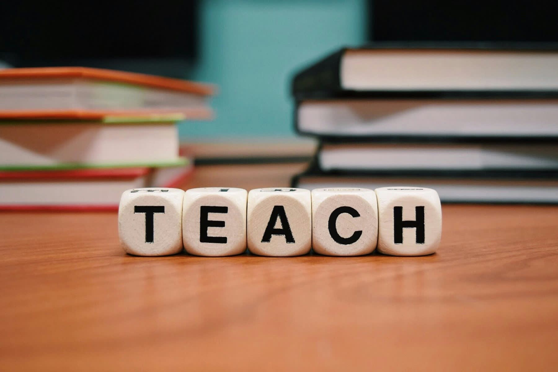 Scrabble pieces spelling out the word TEACH