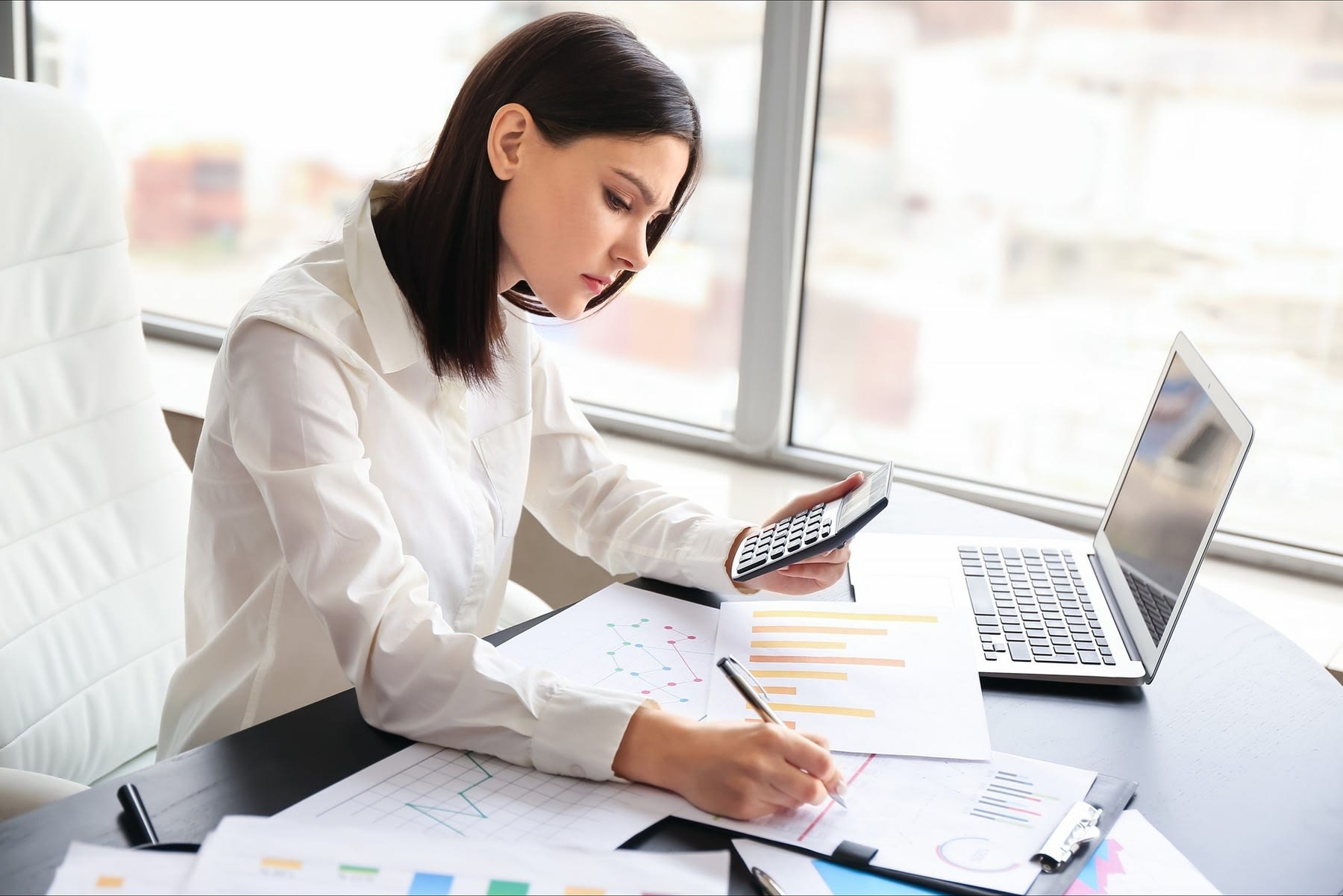 Woman writing down numbers from the calculator she is holding