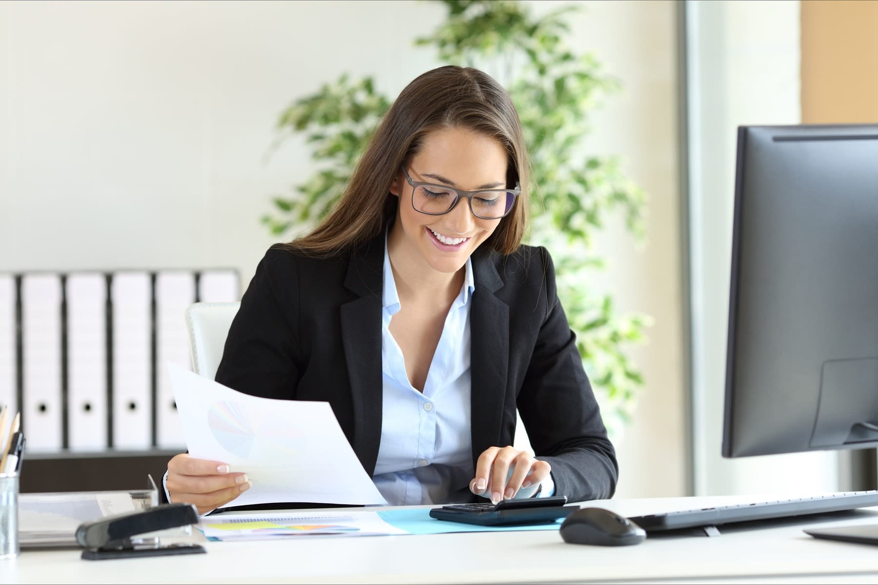 Woman holding a printed paper while using a calculator