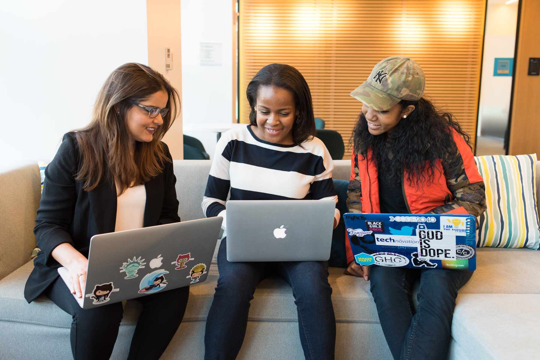 Three women using their laptops while sitting on the couch