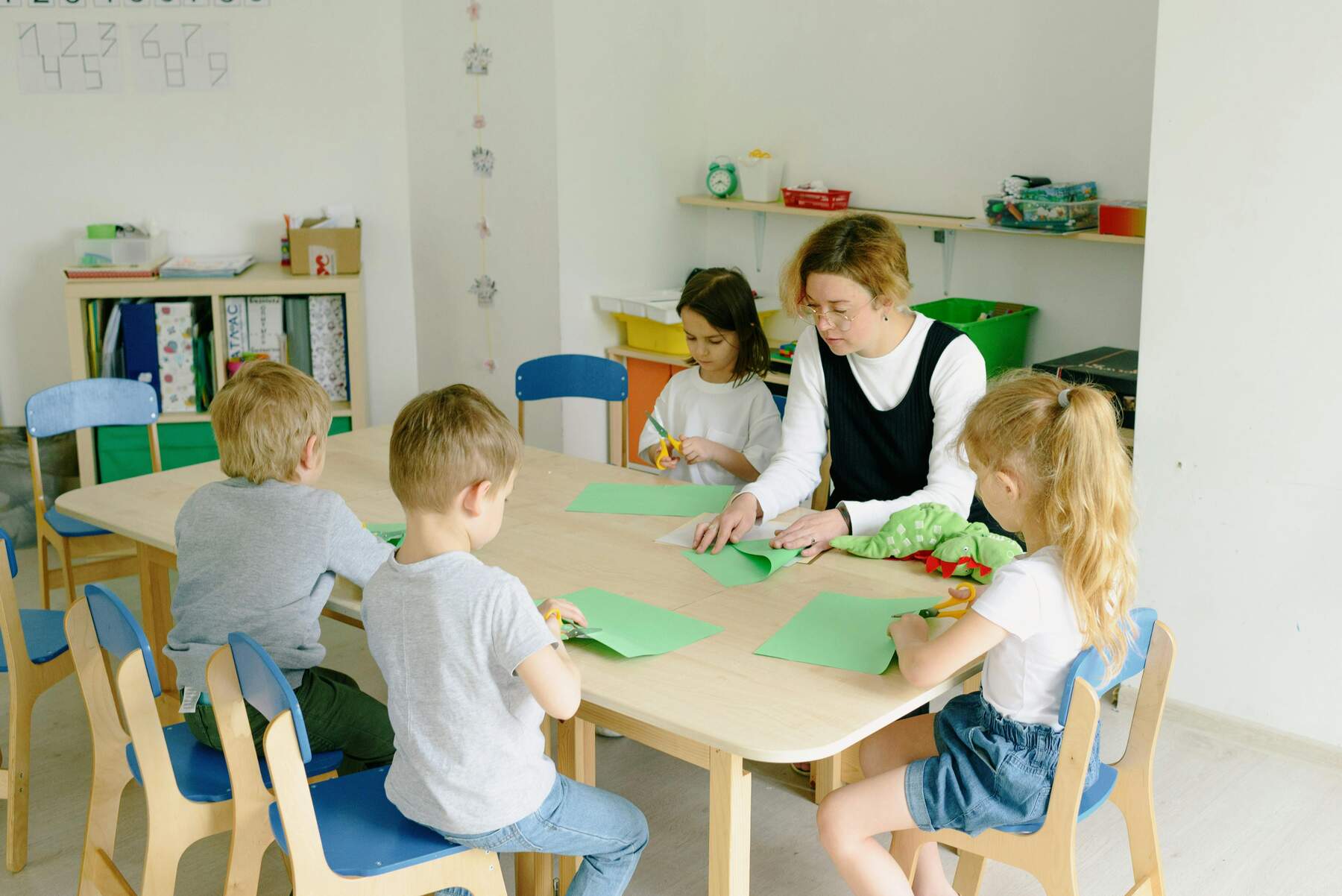 Woman sitting together with kids and teaching them how to fold paper planes