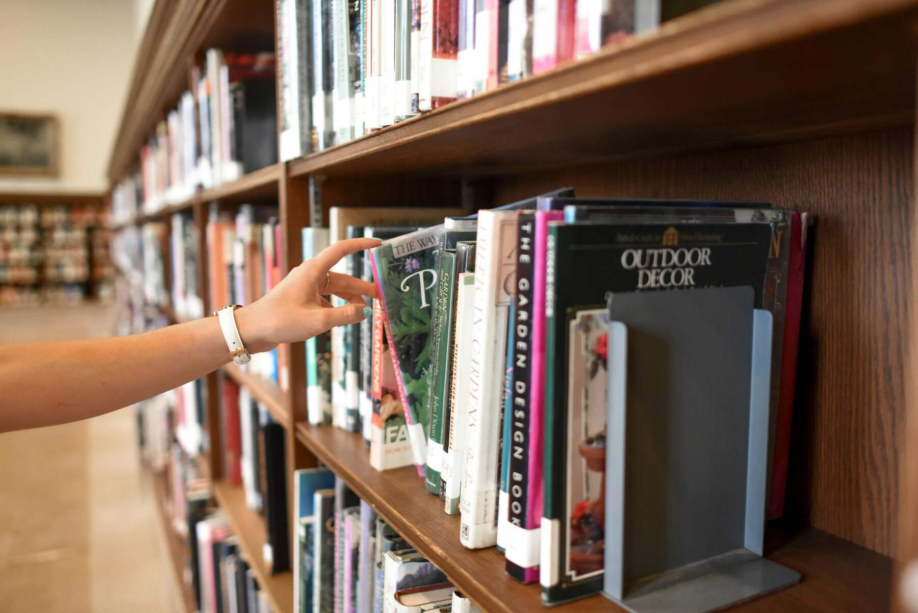 Person taking a book from a bookshelf