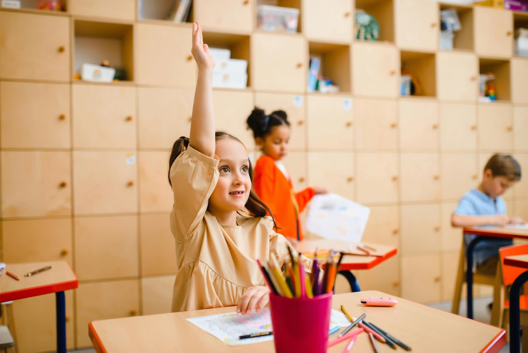 Little girl raising her hand during class