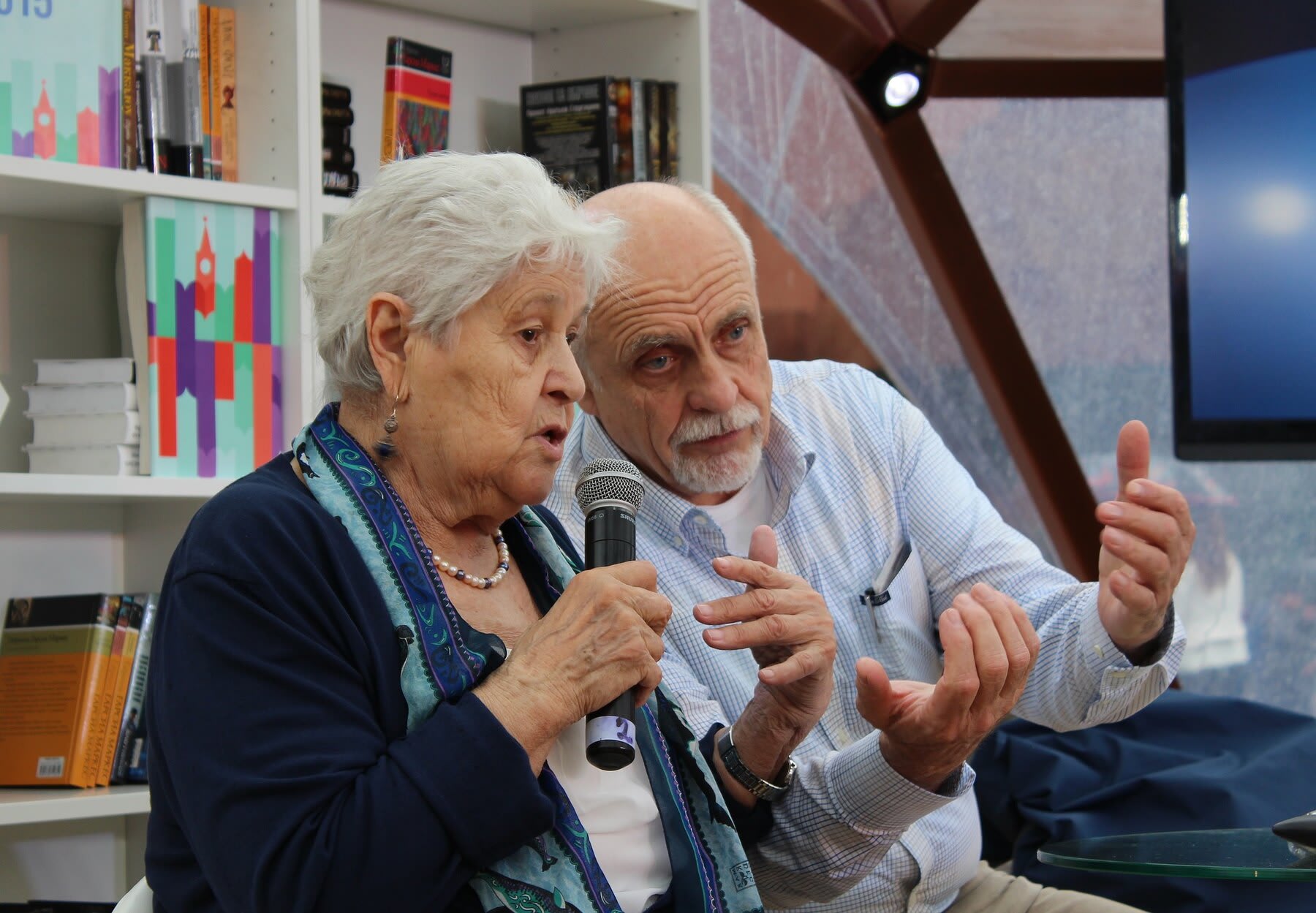 Senior nurse doing a lecture in class, while joined by a male colleague on stage
