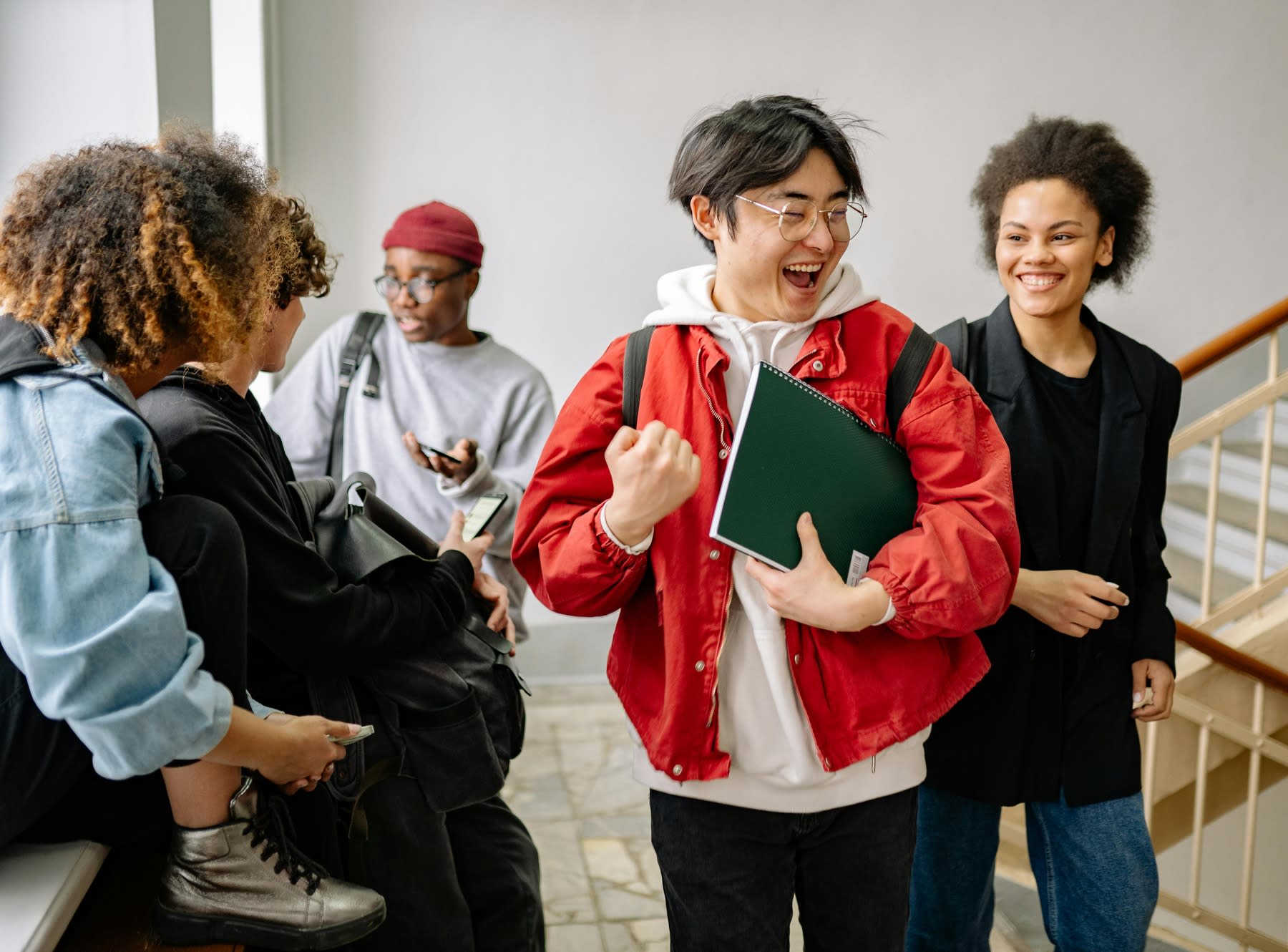 Male student looking happy while walking down a crowded university staircase