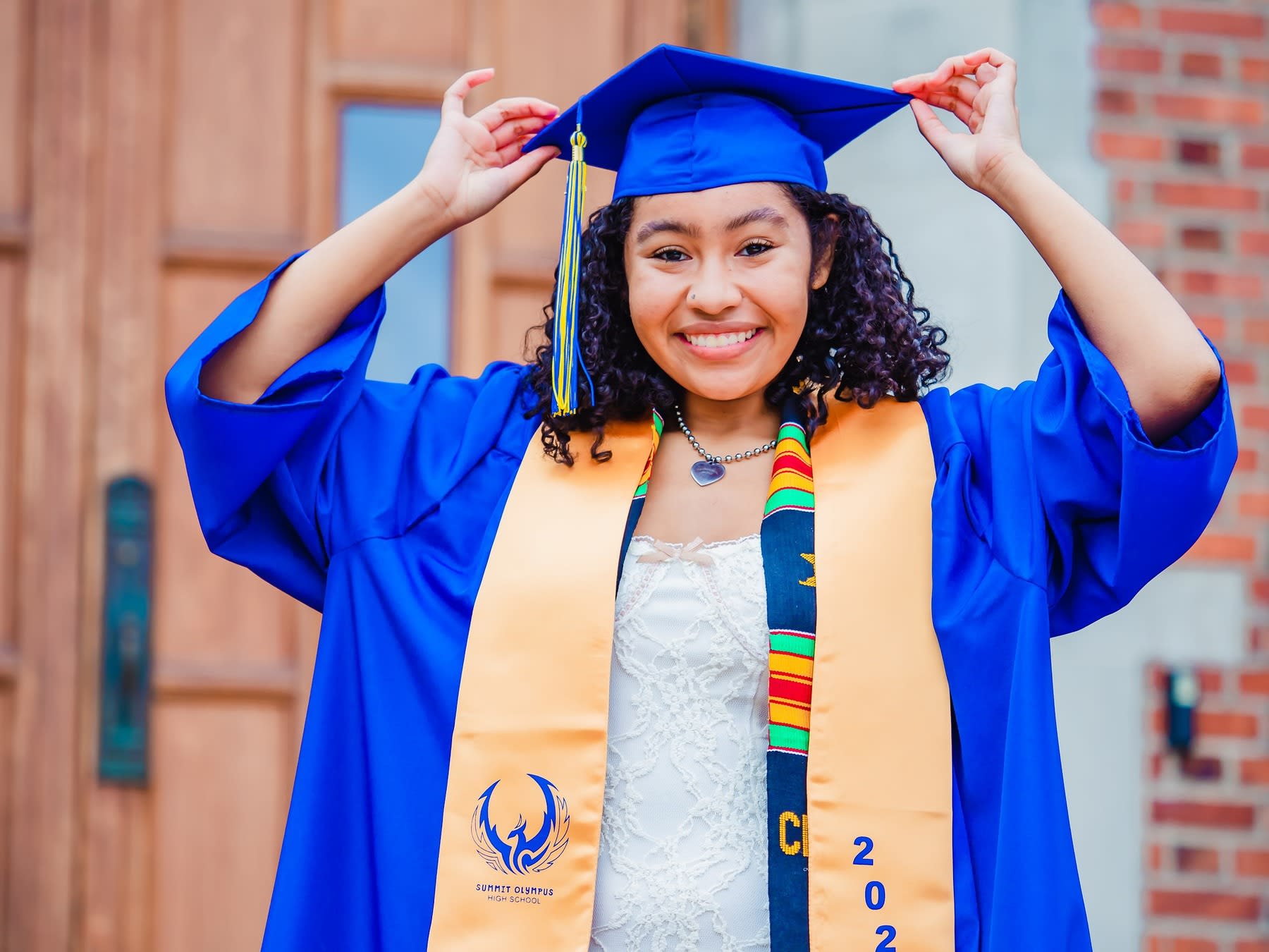 Woman wearing graduation robes while holding on to her graduation cap