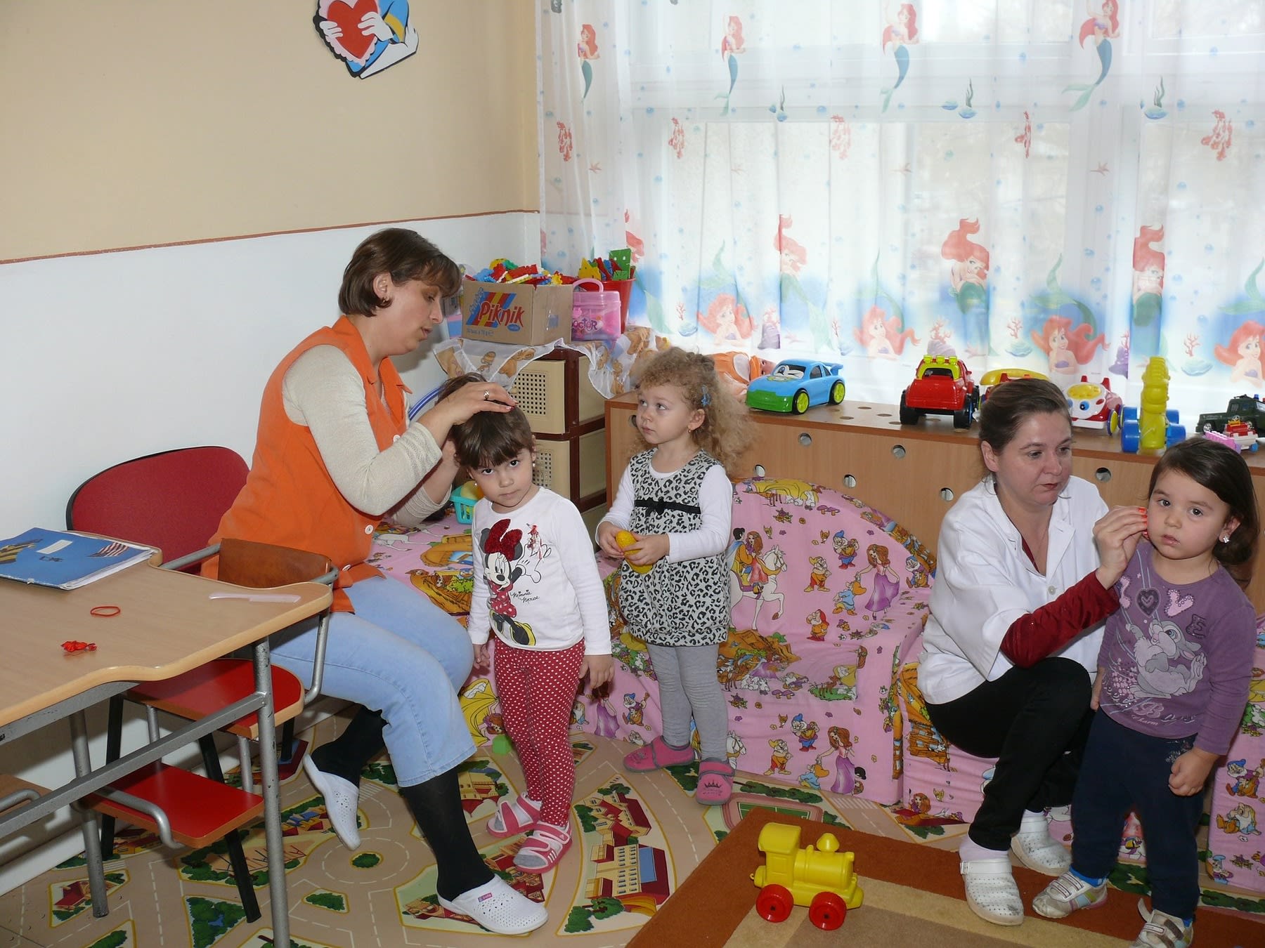 School teachers helping their young students tie their hair after a nap break