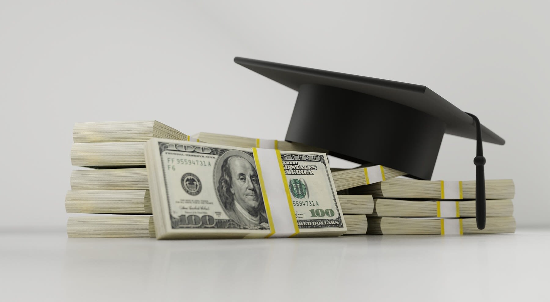 Graduation cap on top of piles of dollar bills