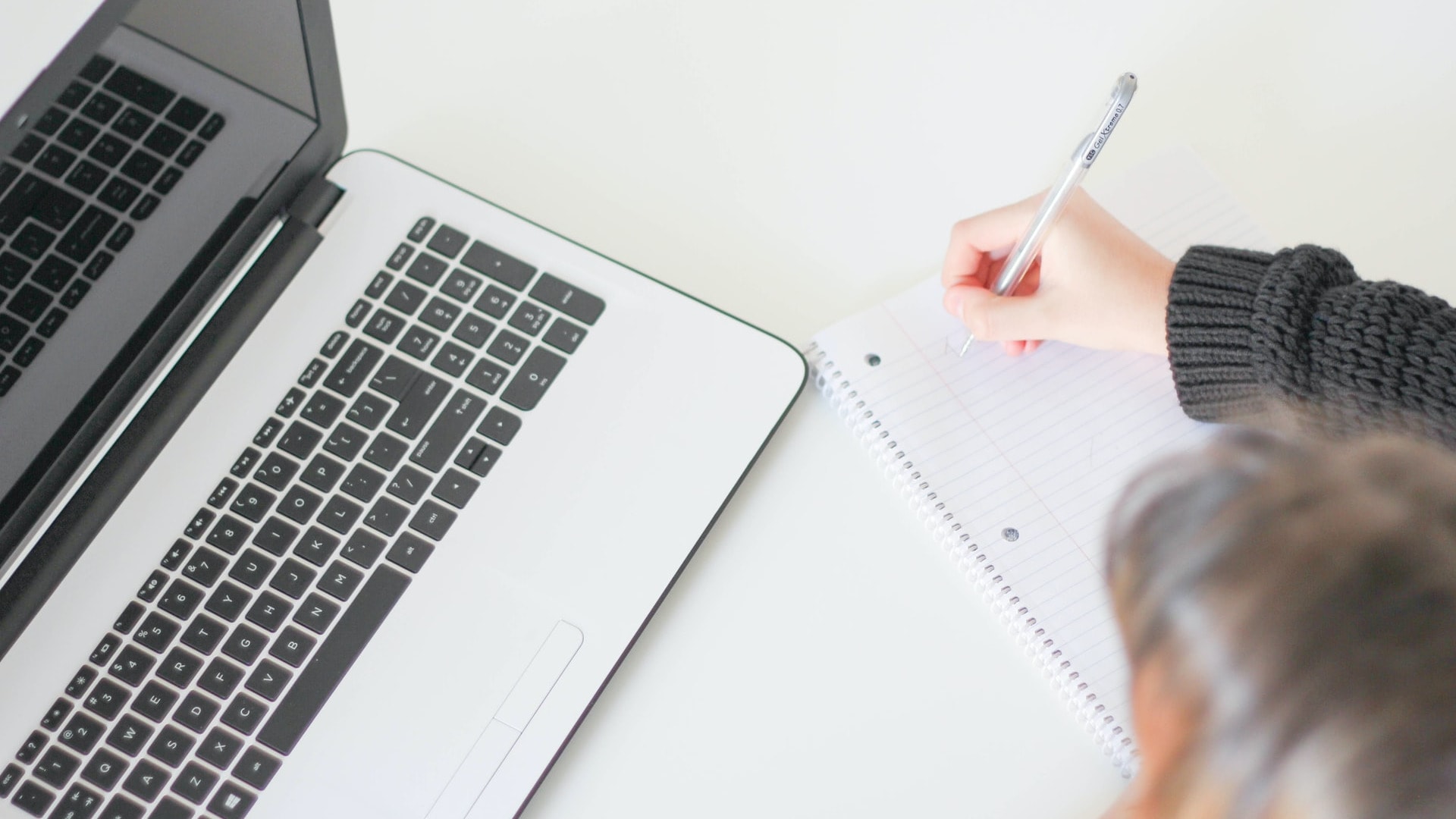 Student taking notes next to a laptop