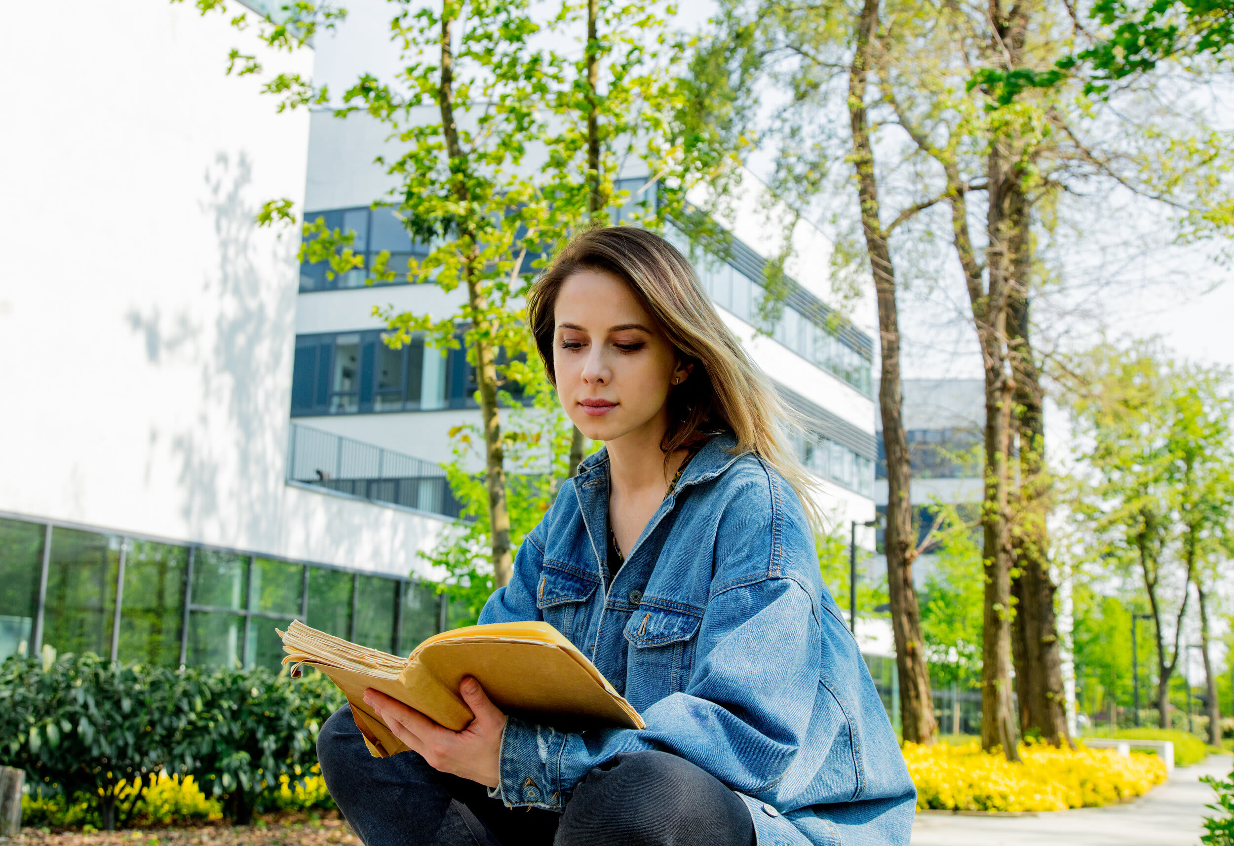Student reading a yellow book outside