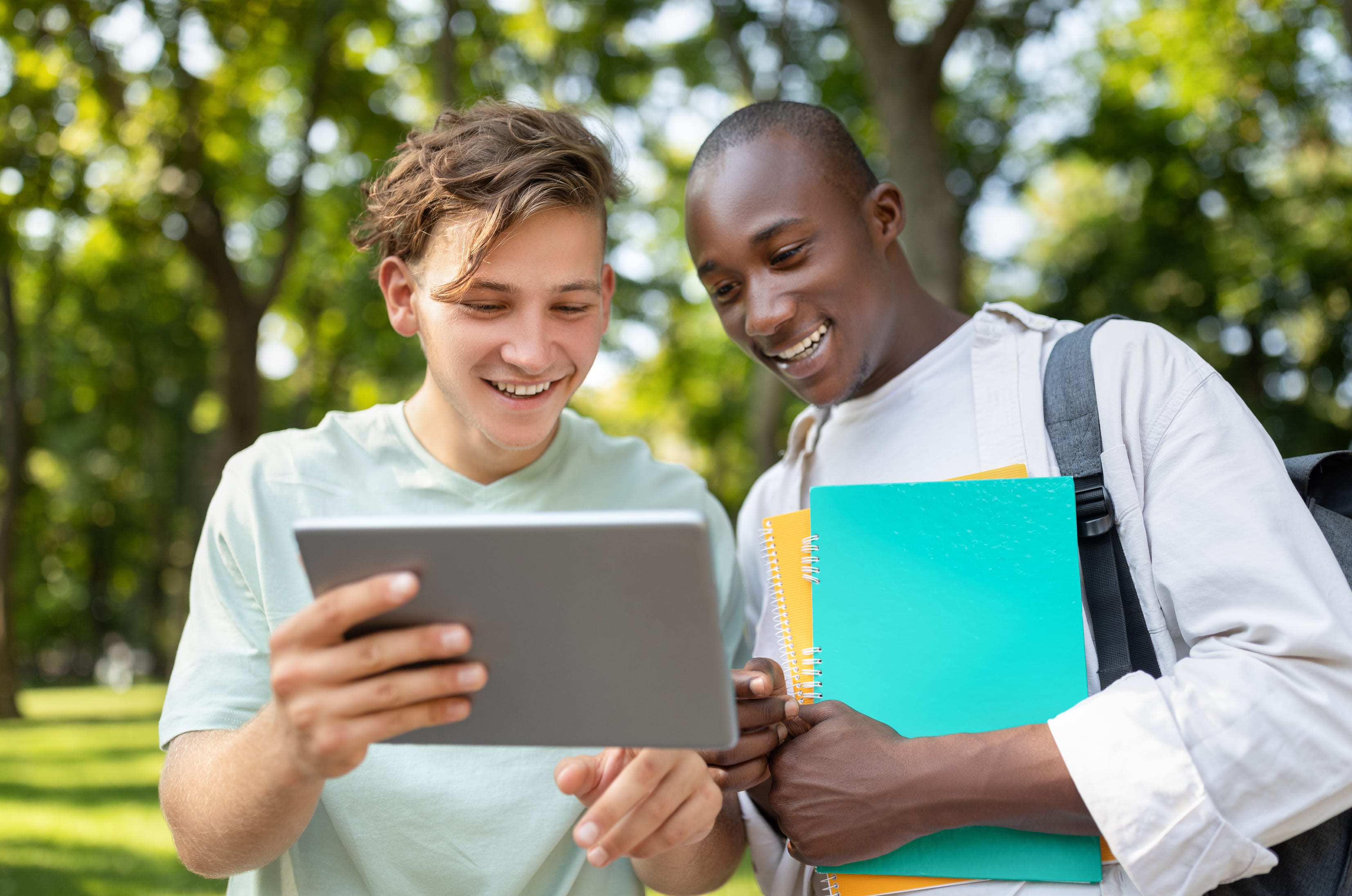 Two student smiling at an electronic tablet