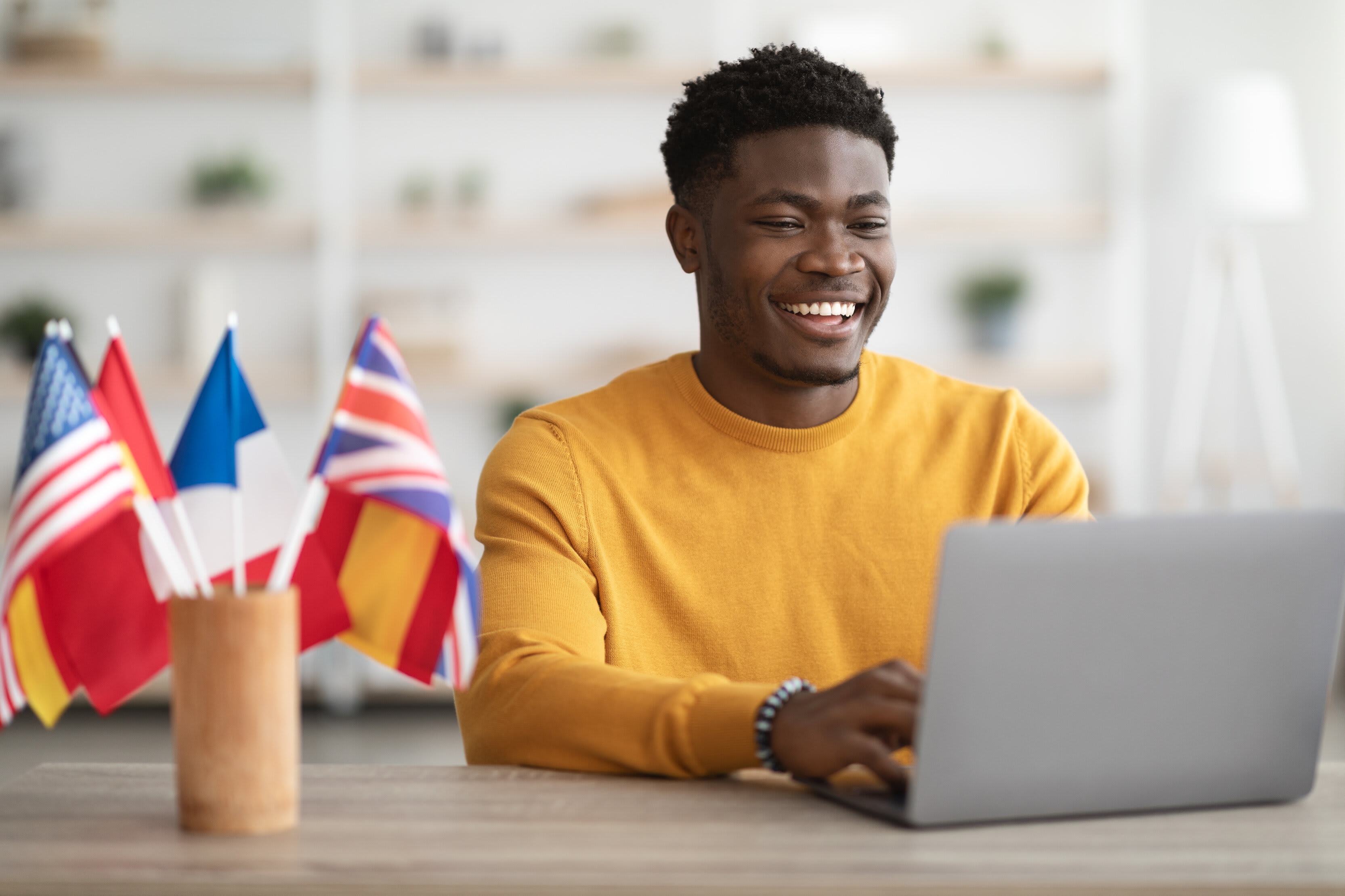 Man in yellow shirt smiling at laptop