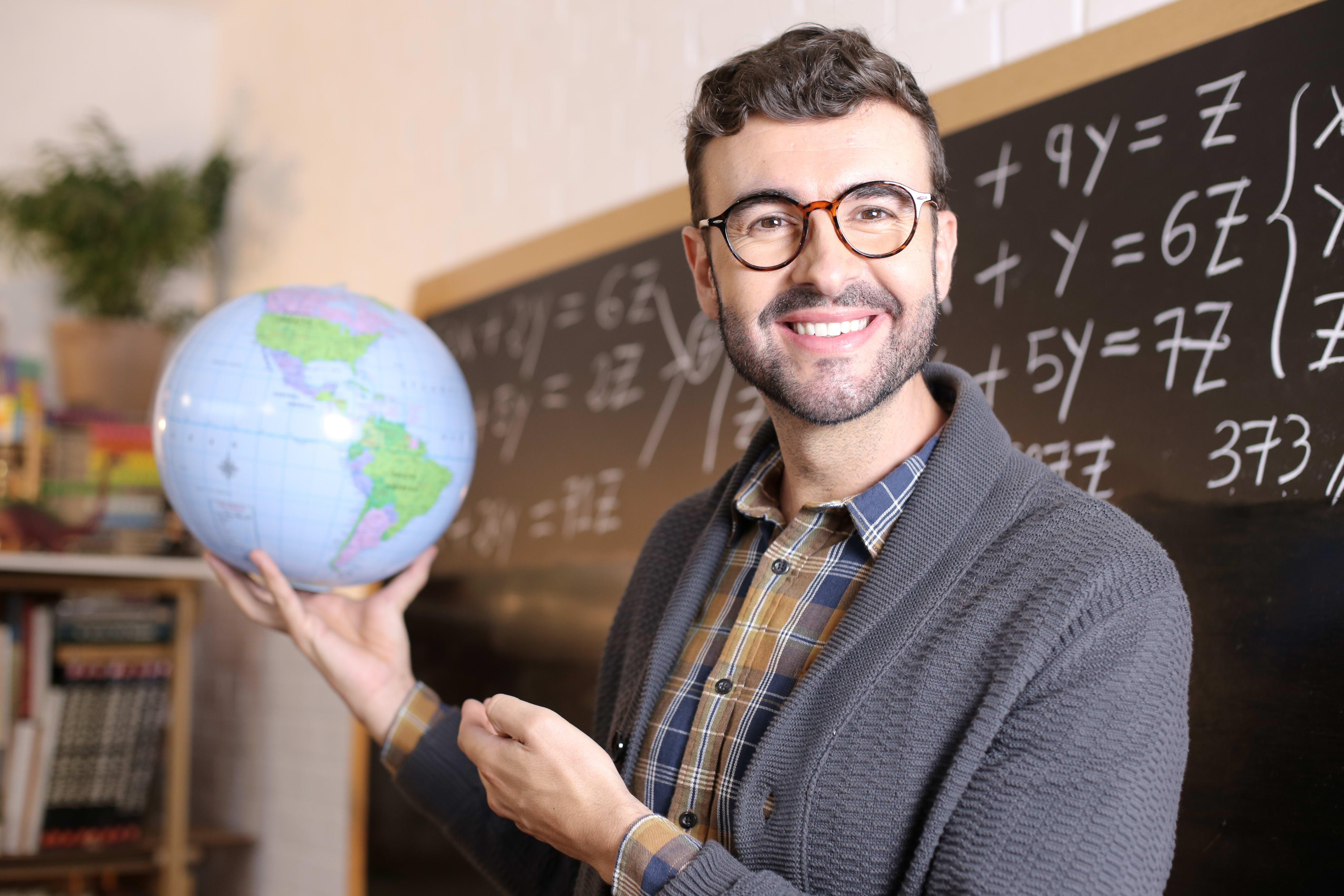 teacher holding a globe in a classroom