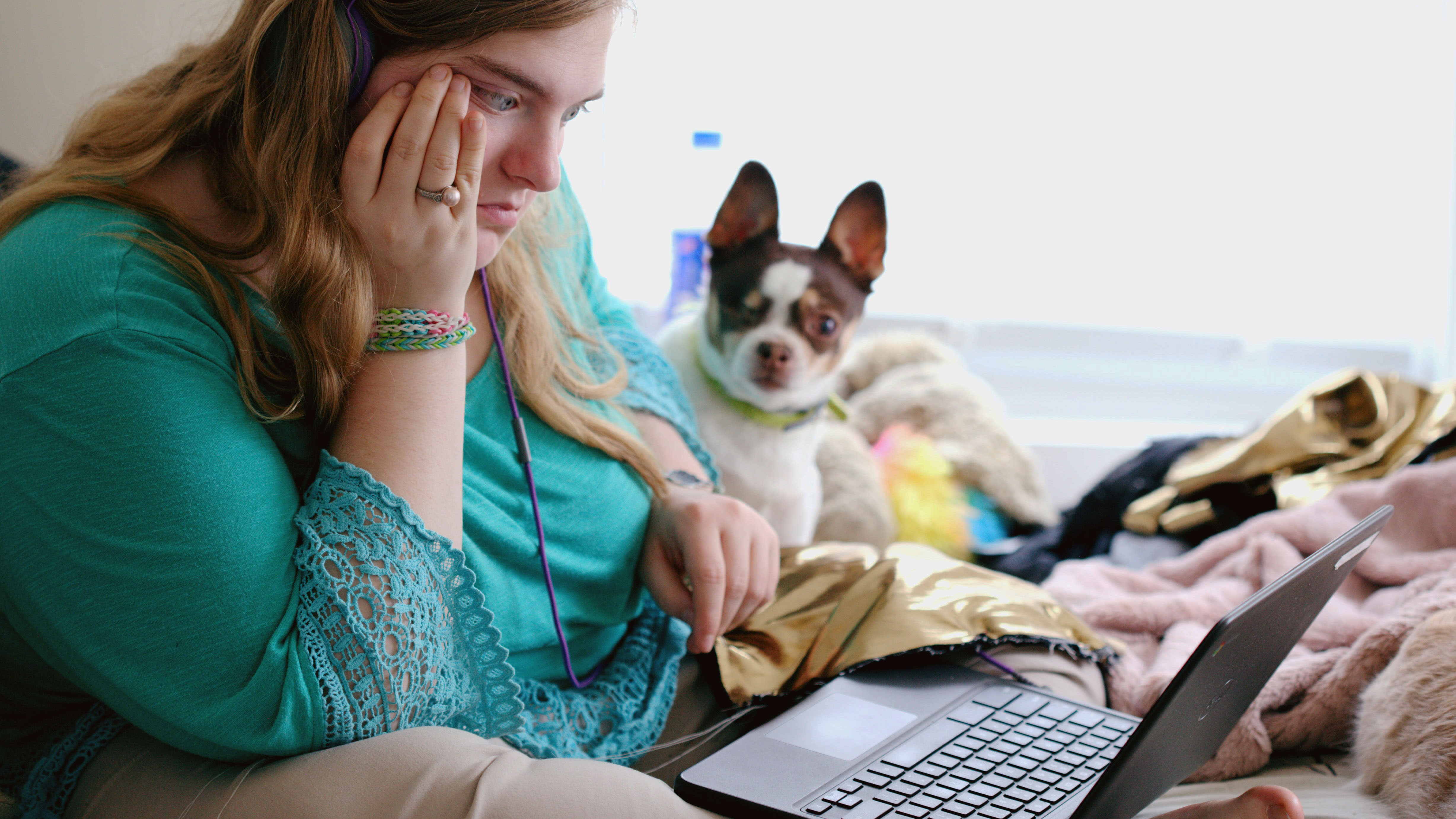 Student working on a bed next to a dog