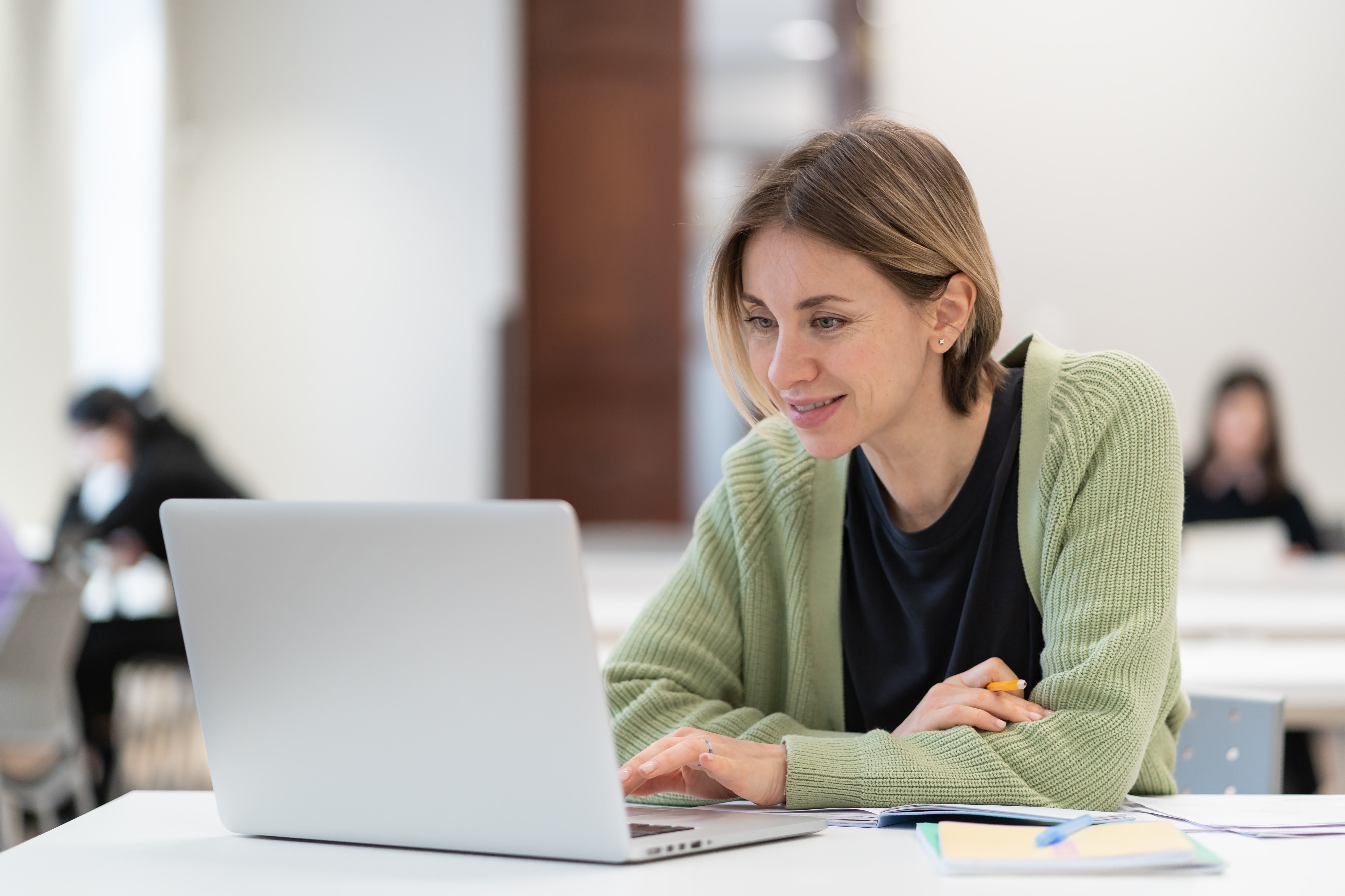 Female student in green sweater studying on a laptop