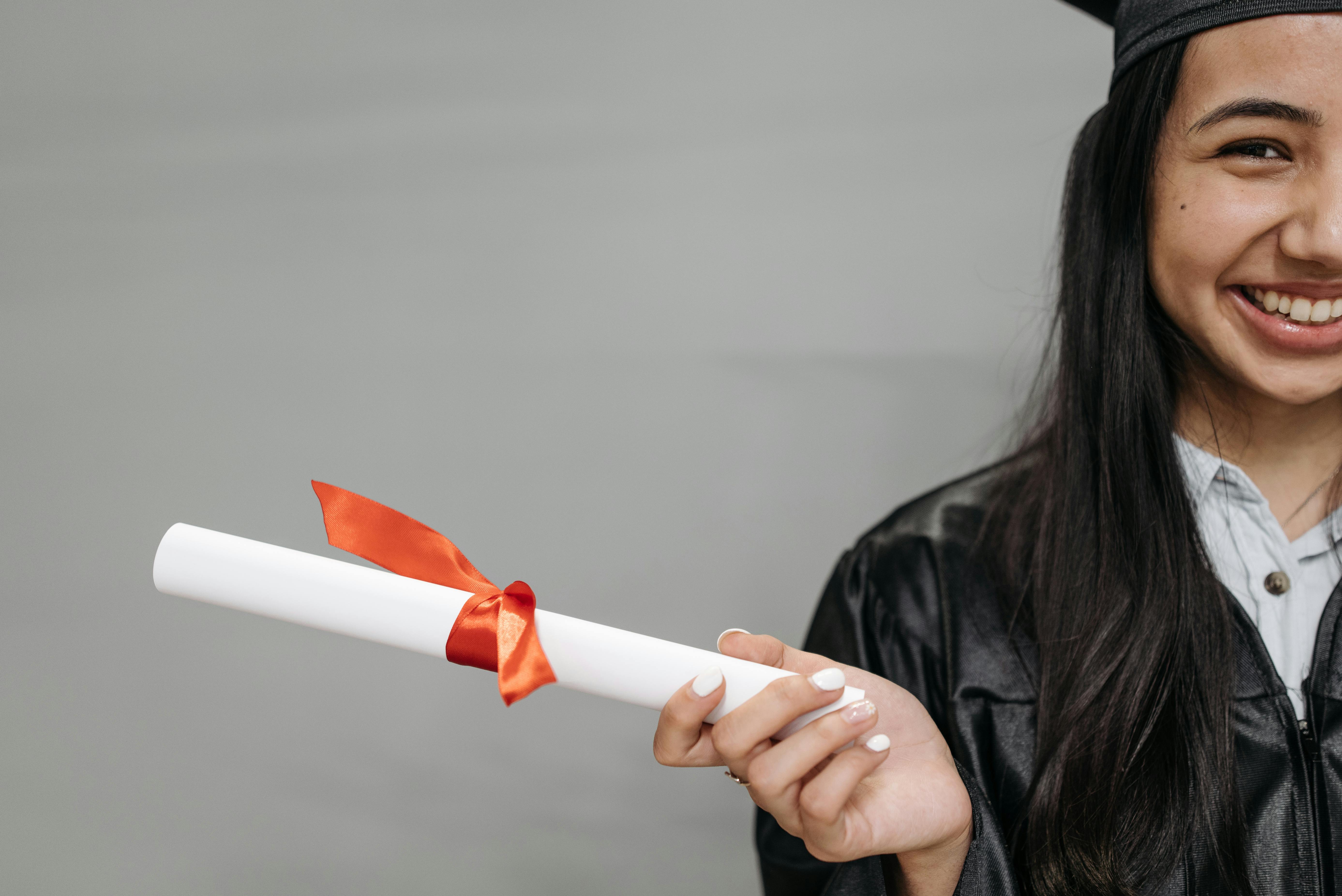 Young woman wearing graduation robes, and holding a diploma