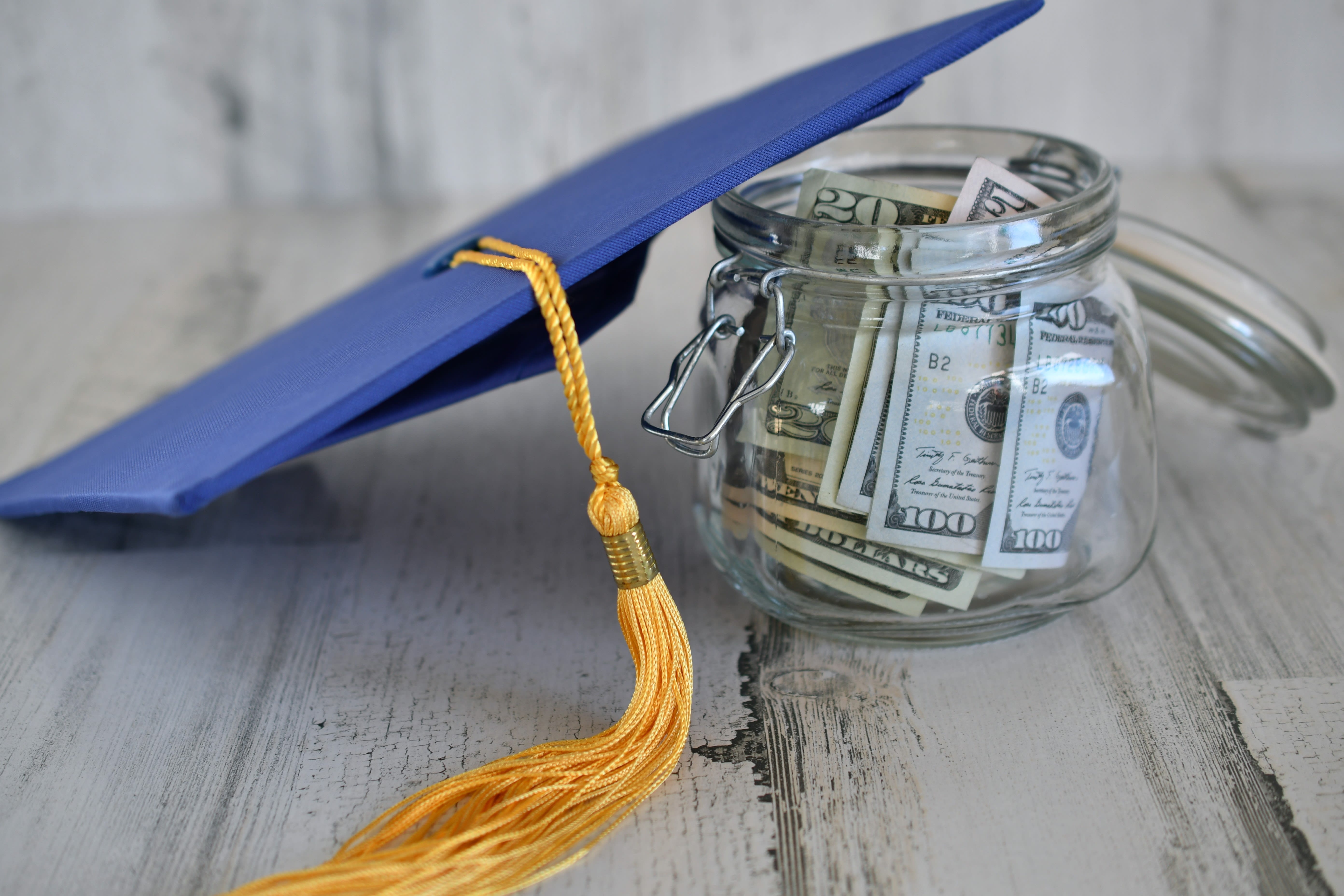 Graduation cap next to a jar of U.S. dollars