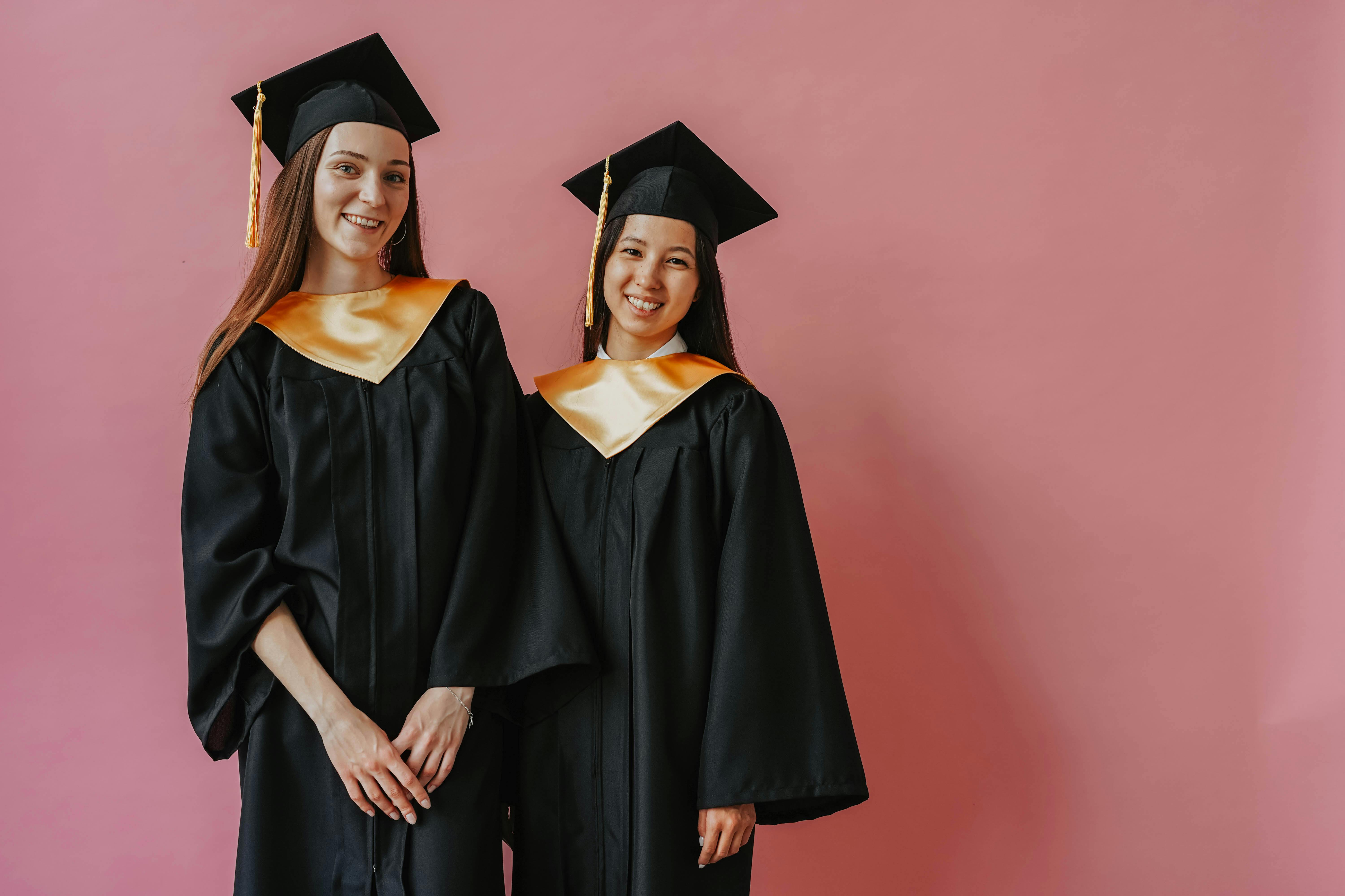 Two women wearing graduation robes while posing for their photos