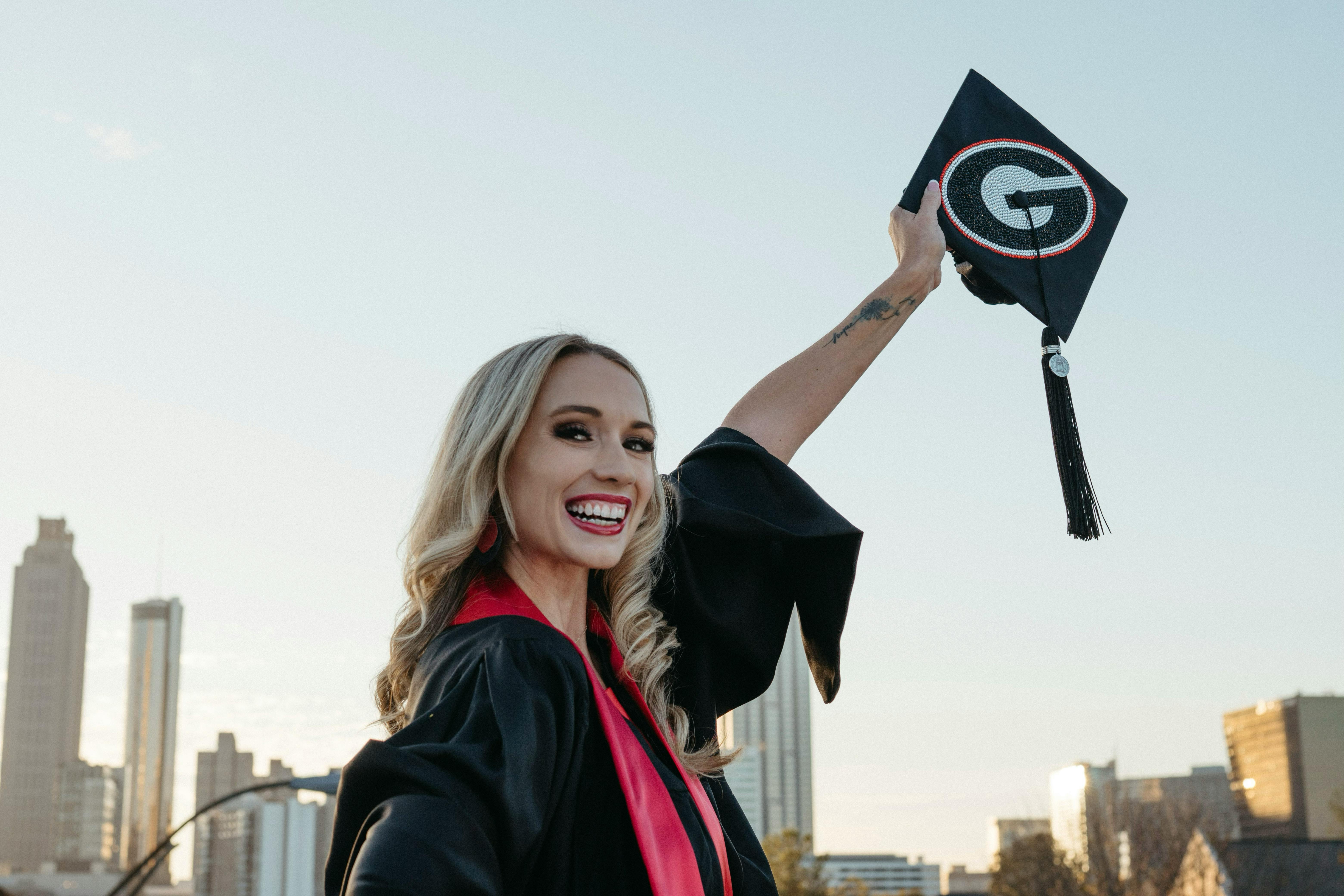 Woman wearing graduation robes and holding her graduation cap