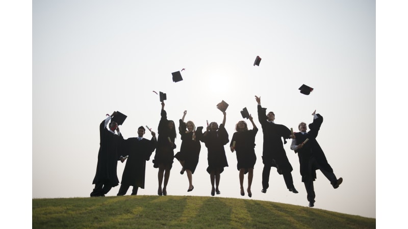 College graduates celebrating by throwing their caps in the air