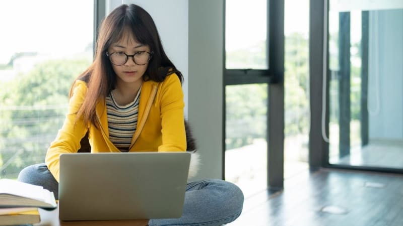 Female student on laptop in a hallway